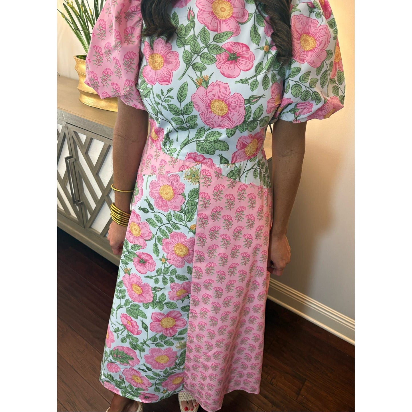Person wearing a pink floral dress standing indoors.