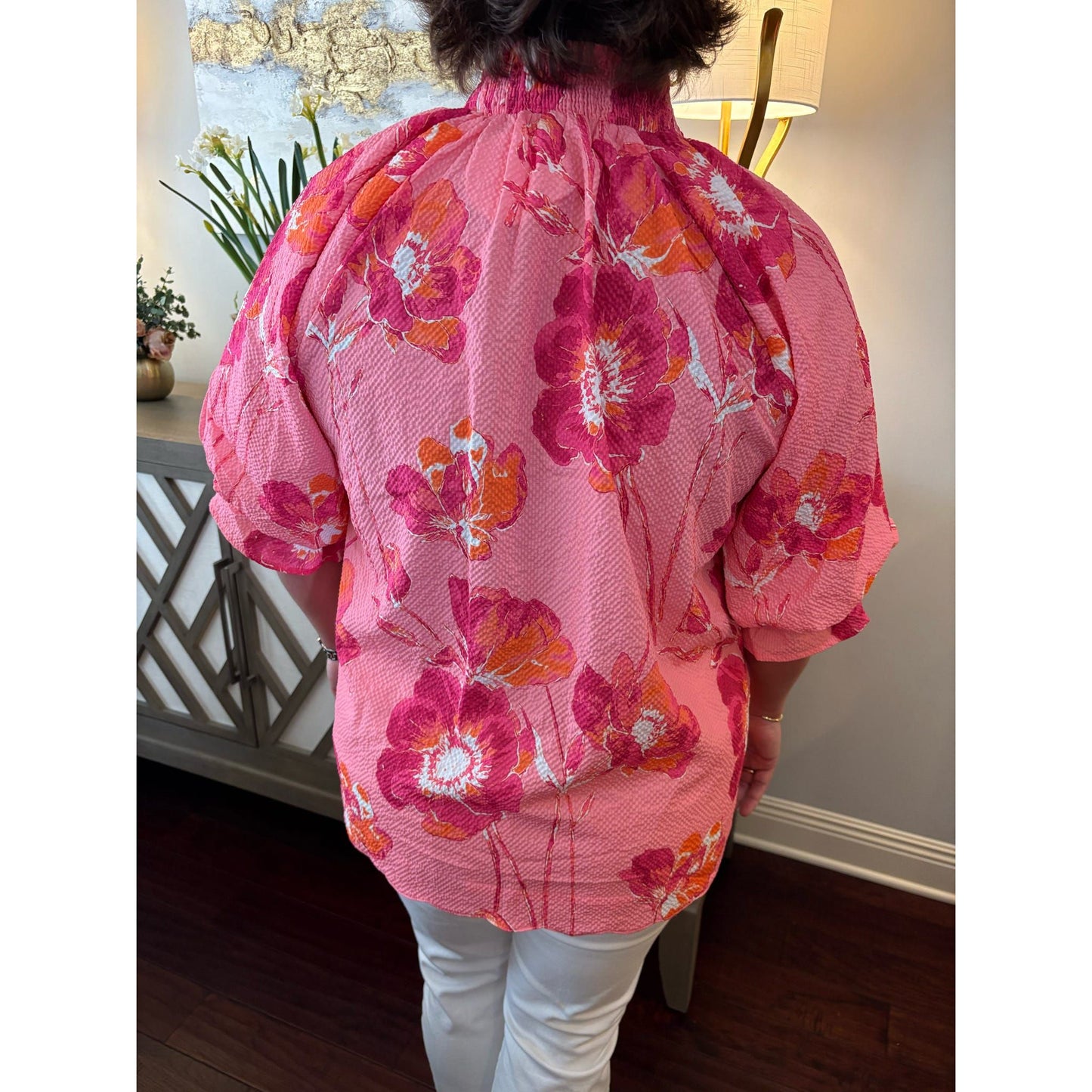 Person wearing a pink floral kimono-style garment indoors.