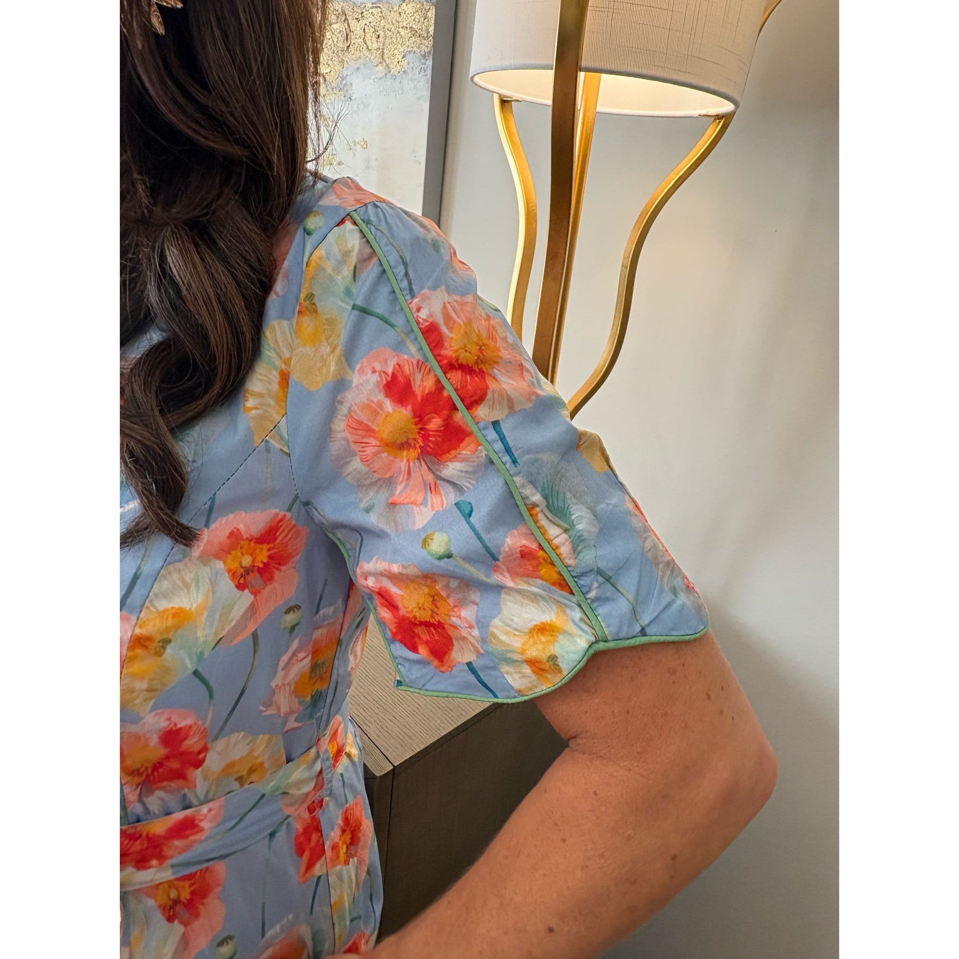 Person wearing a floral kimono-style garment with a lamp in the background