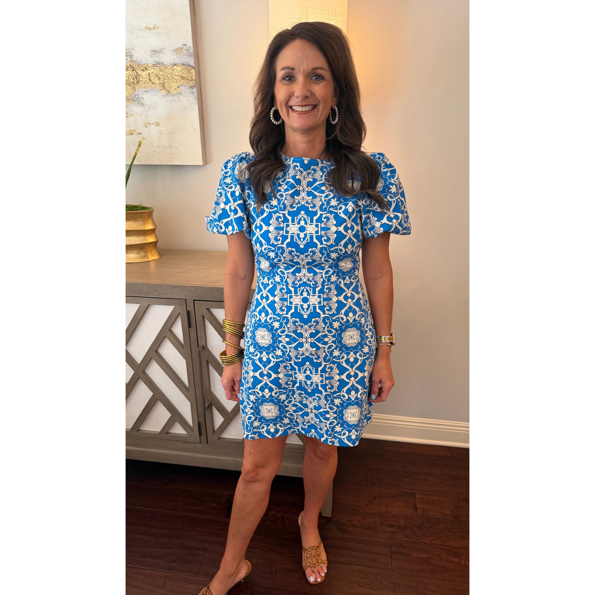 Woman wearing a blue and white patterned dress standing indoors.