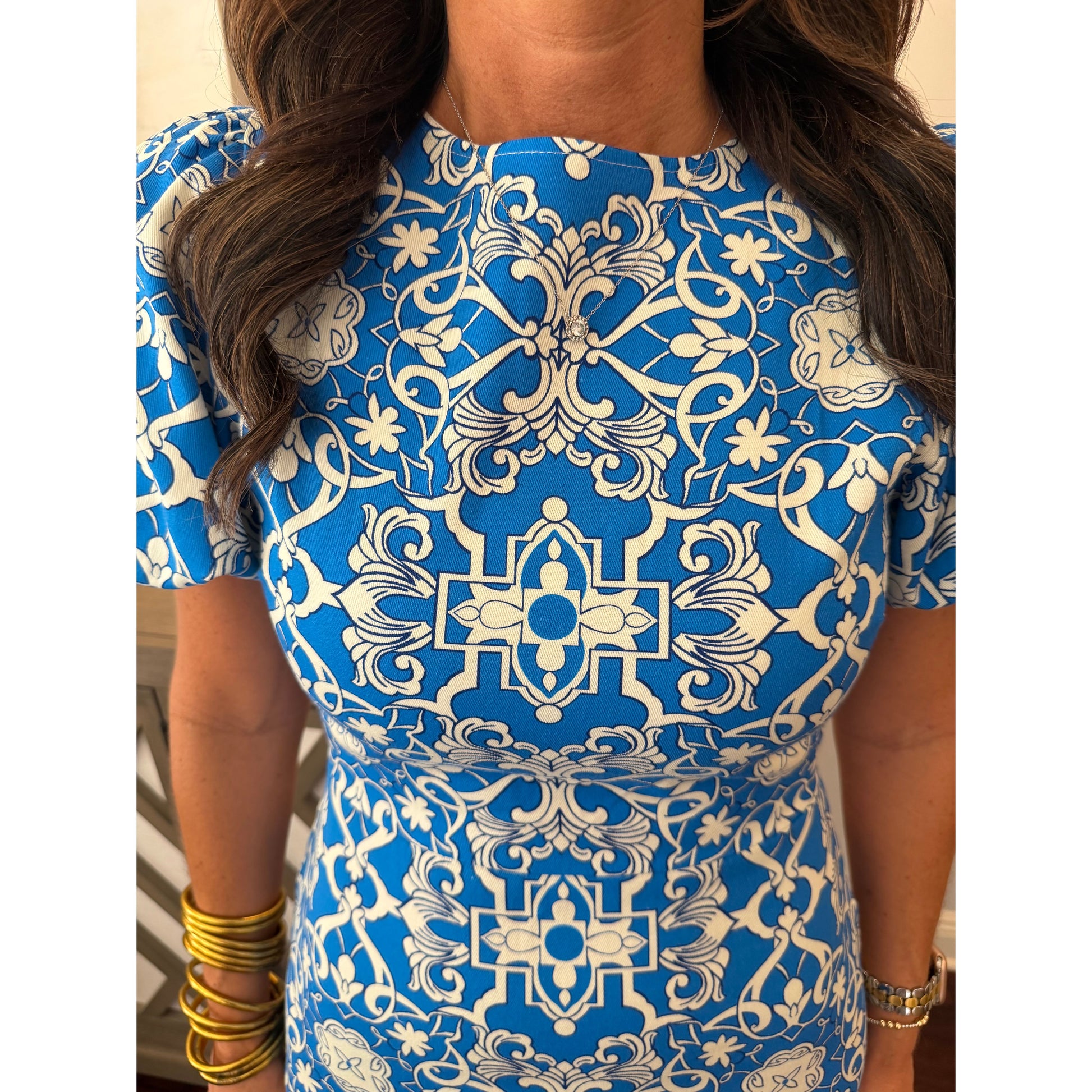 Person wearing a blue and white patterned dress with a neutral background