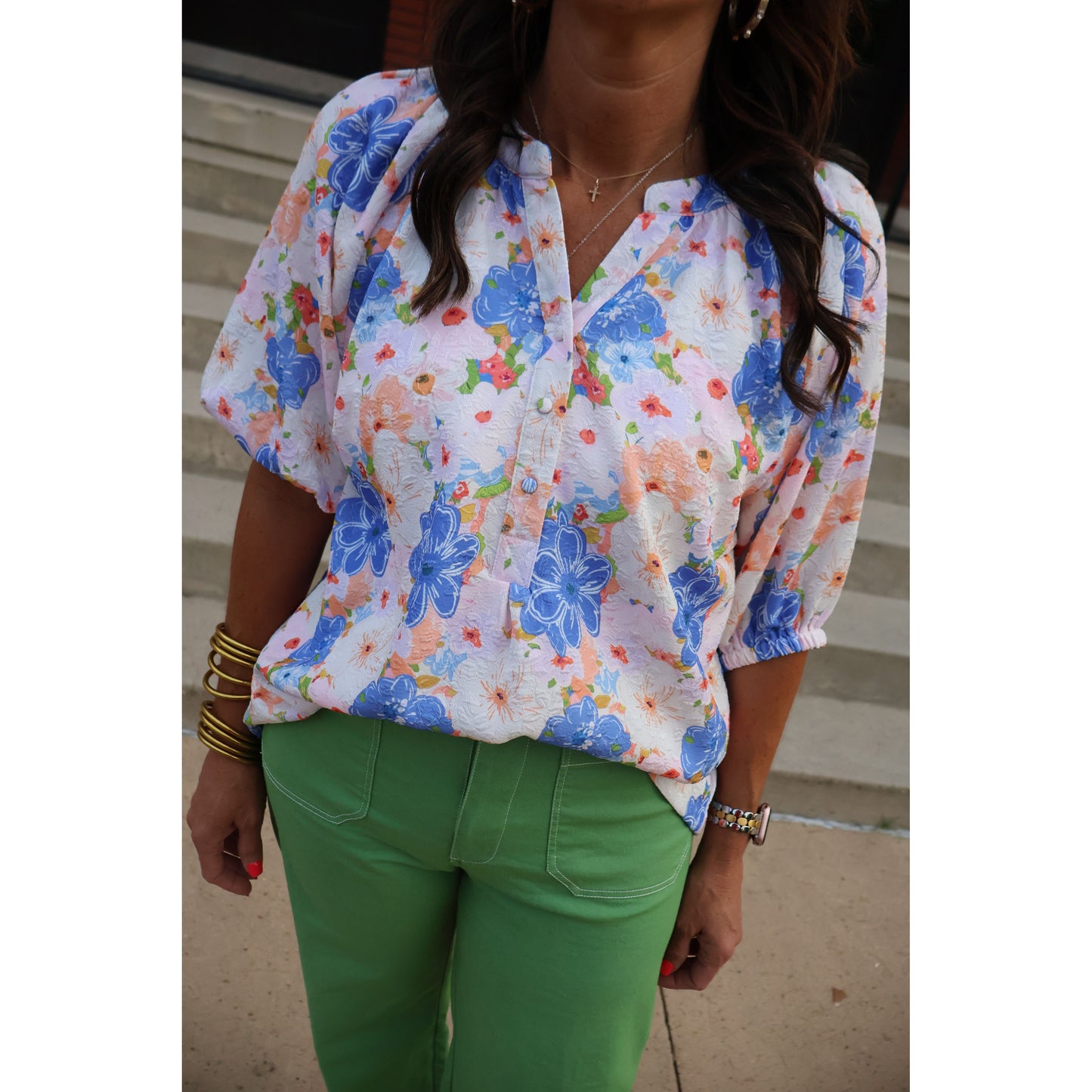 Person wearing a colorful floral dress with green pants on a neutral background