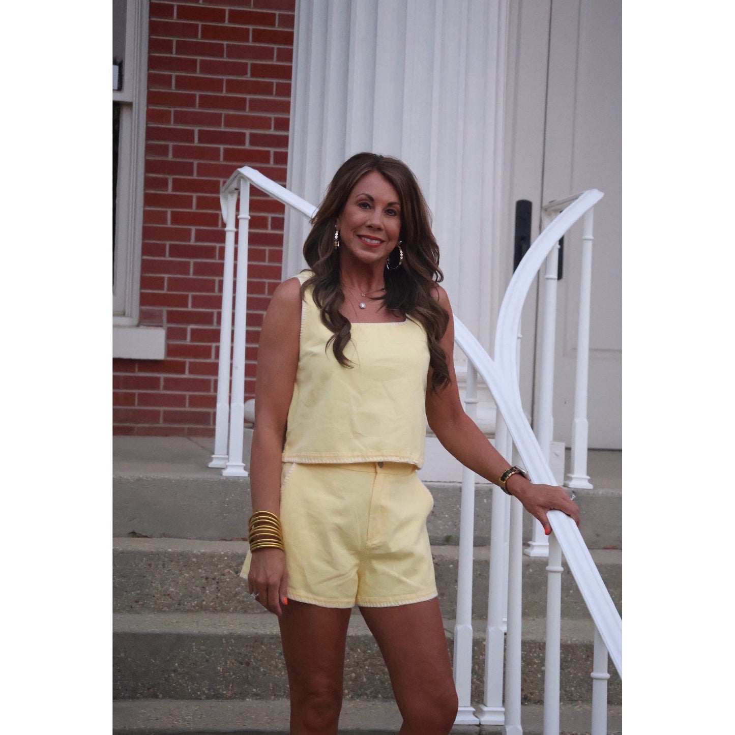 Woman in a yellow outfit standing on steps with a white railing.