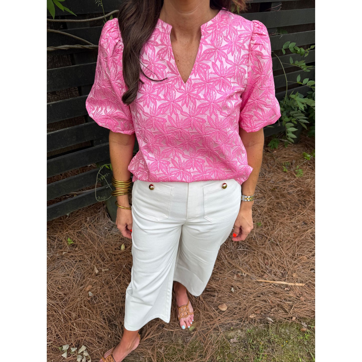 Person wearing a pink floral jacket and white pants sitting on the ground.