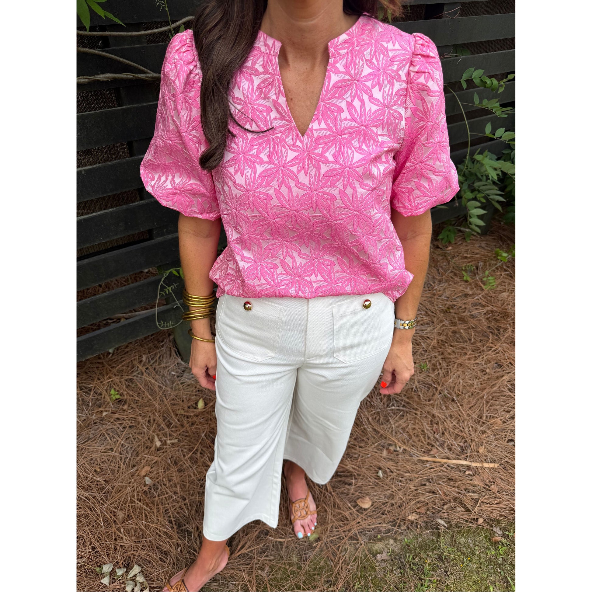 Person wearing a pink floral jacket and white pants sitting on the ground.