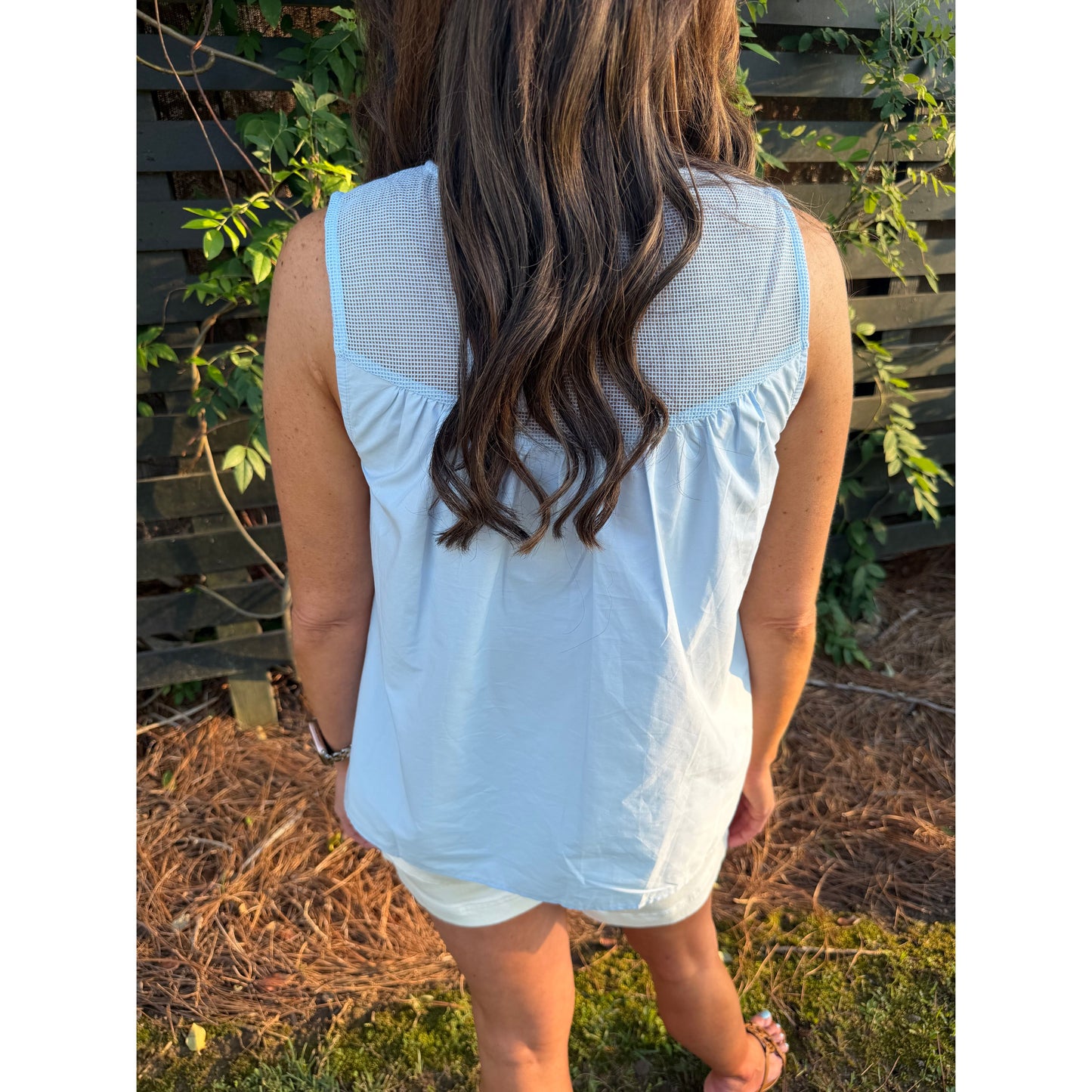 Person wearing a light blue dress with a garden background