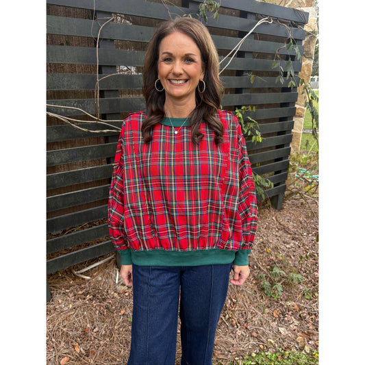 Woman wearing a red plaid shirt and blue jeans standing on a wooden platform.