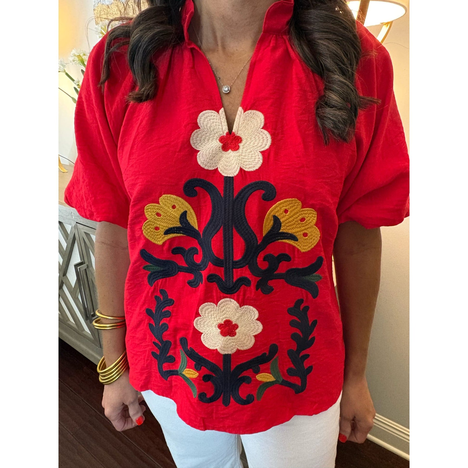Red blouse with floral embroidery worn by a person indoors.