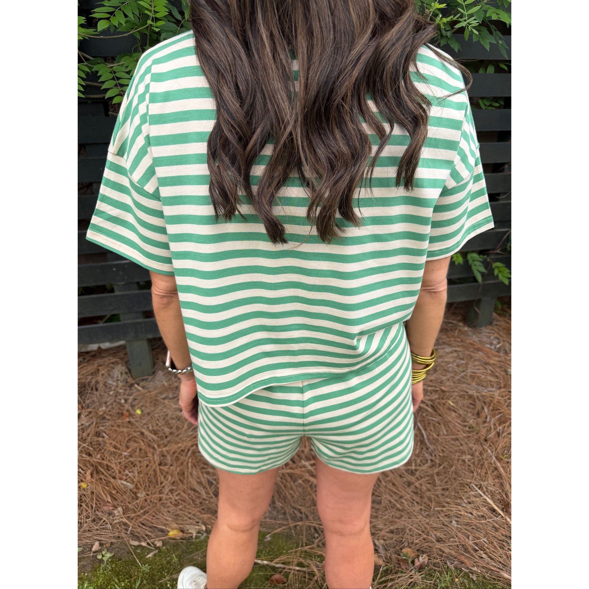 Green and white striped dress worn by a person, with a focus on the fabric pattern.