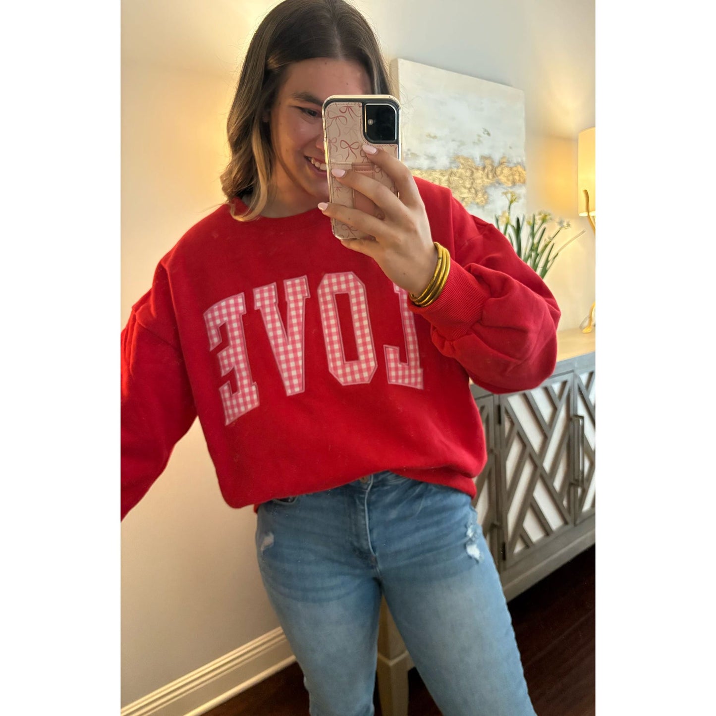 Person wearing a red sweatshirt with 'LOVE' printed on it, taking a mirror selfie.