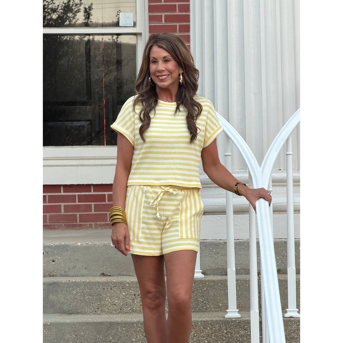 Woman in a yellow striped outfit standing on a porch.