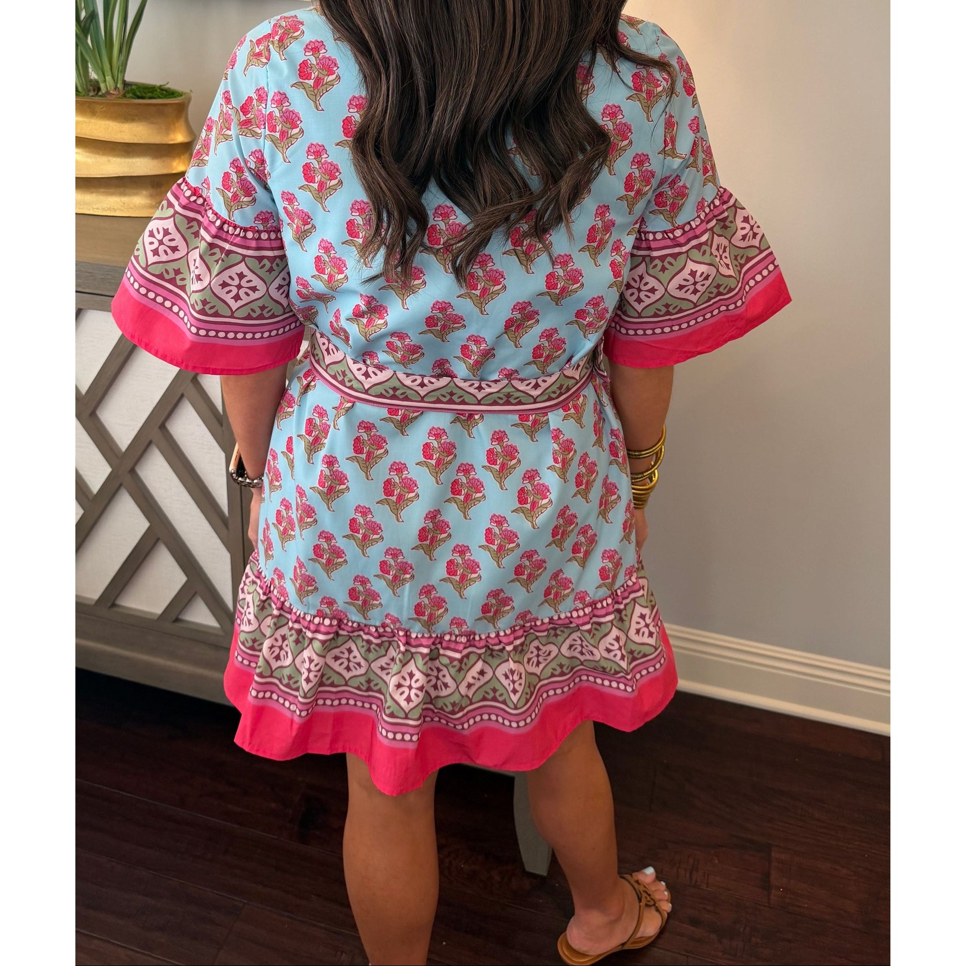 Person wearing a blue and pink patterned dress with a blurred background