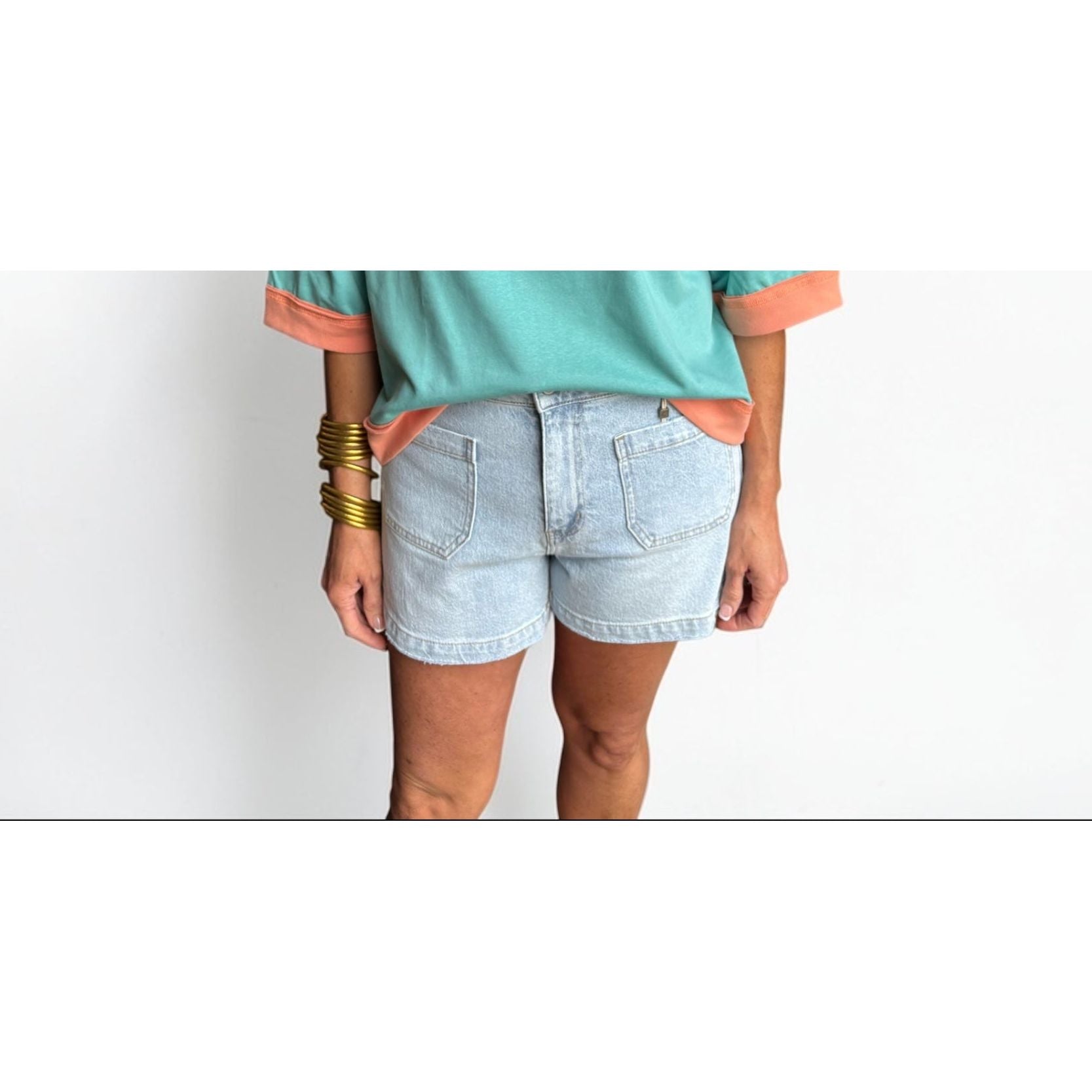 Woman wearing a colorful striped shirt and denim shorts on a white background