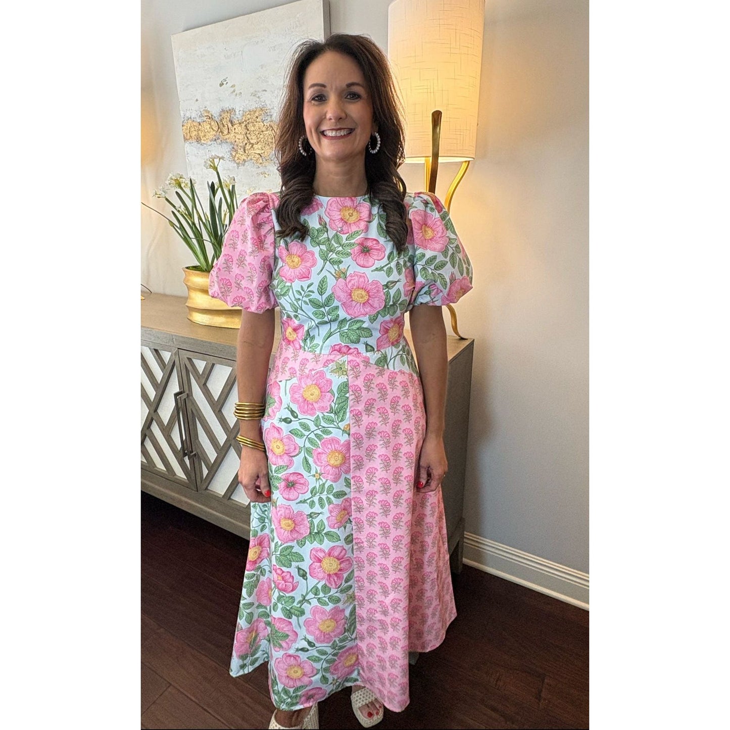 Woman wearing a floral dress in a room with decor elements.