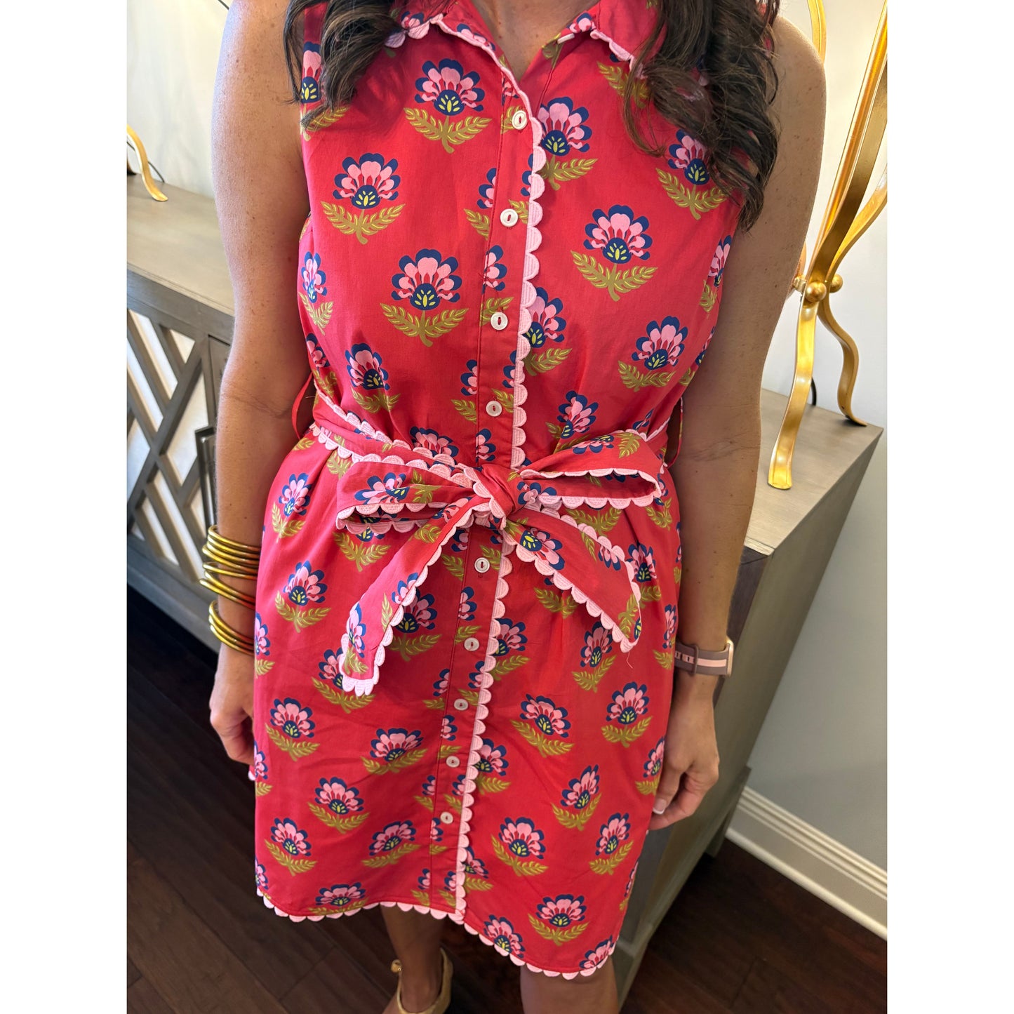 Person wearing a red floral dress sitting on a chair.