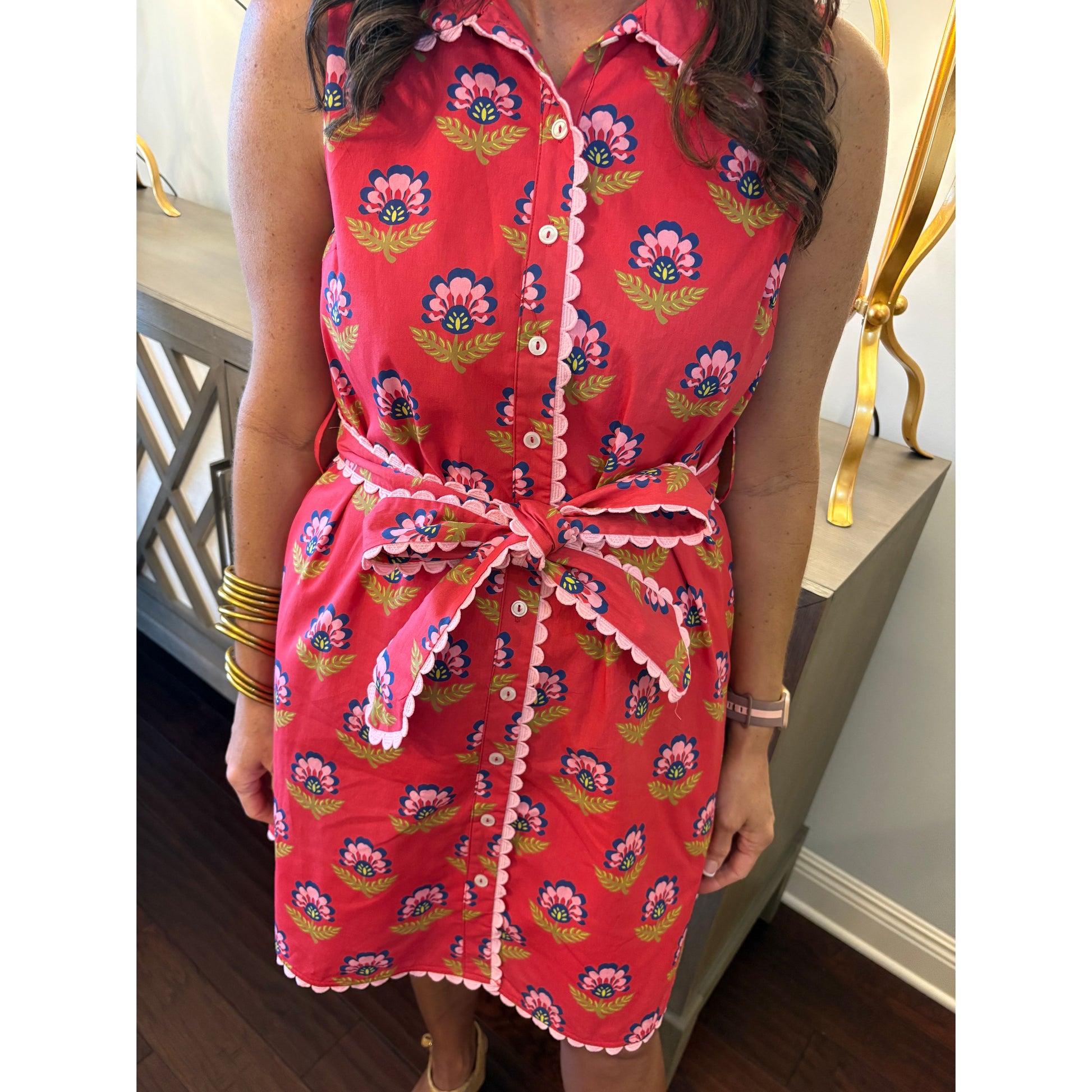 Person wearing a red floral dress sitting on a chair.