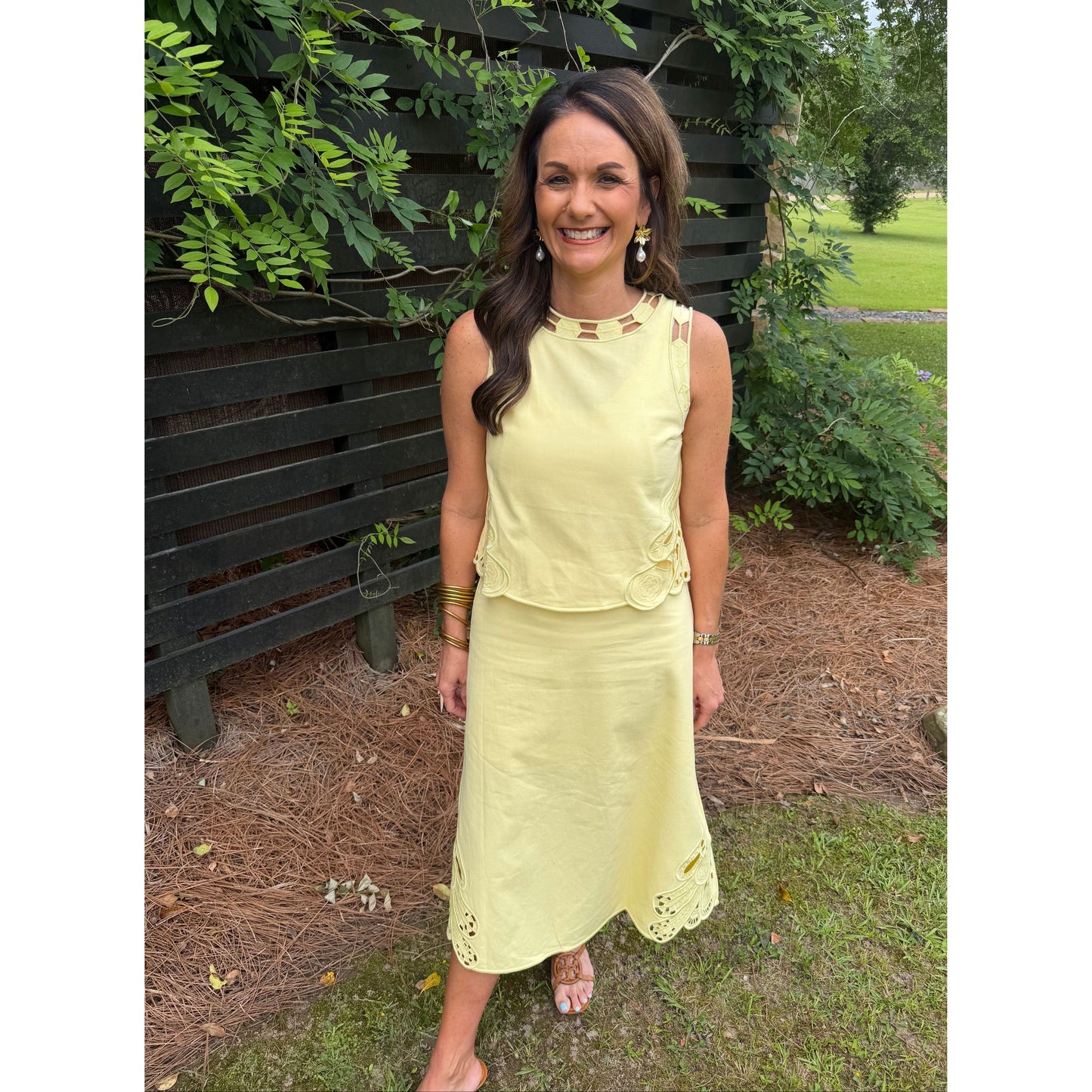 Woman in a yellow dress standing outdoors with greenery around