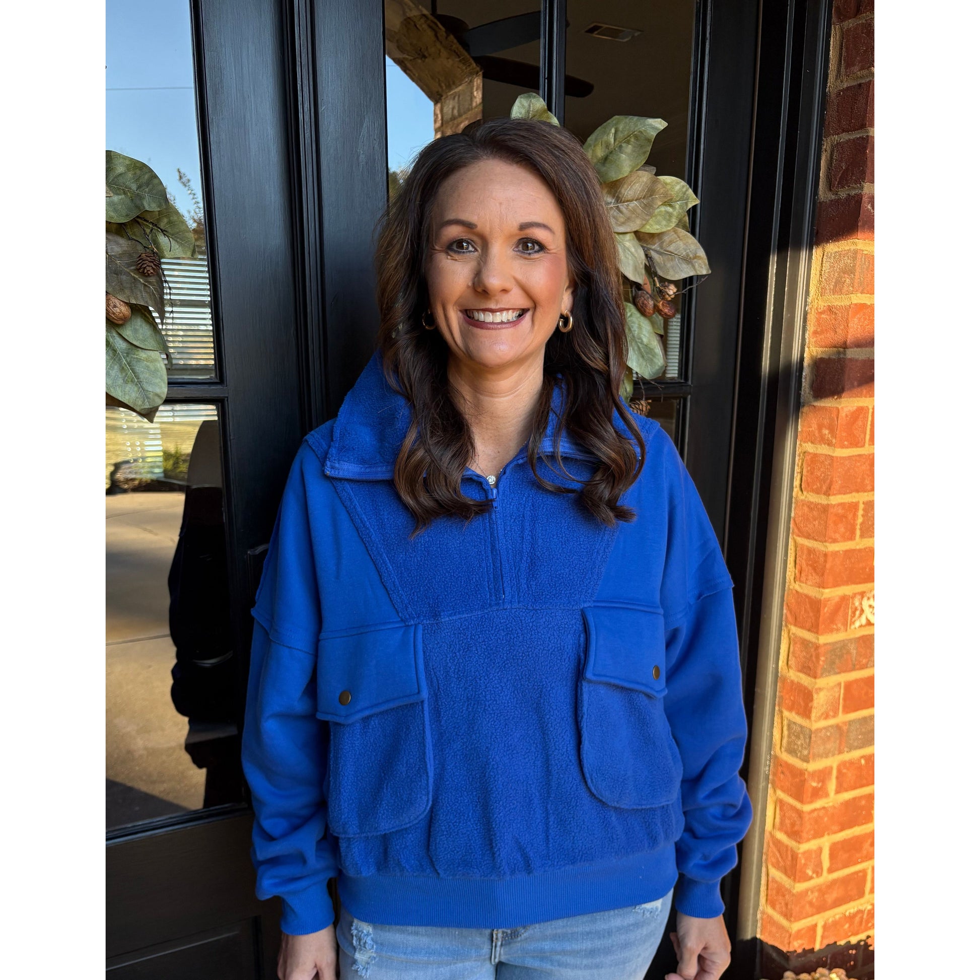 Woman wearing a blue jacket standing in front of a door with a brick wall background