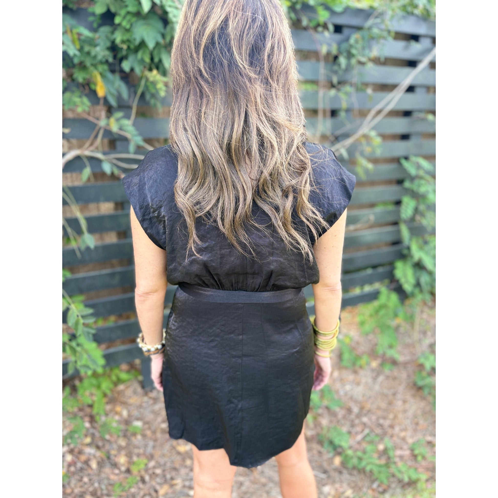 Person wearing a black sleeveless top and skirt with a blurred background