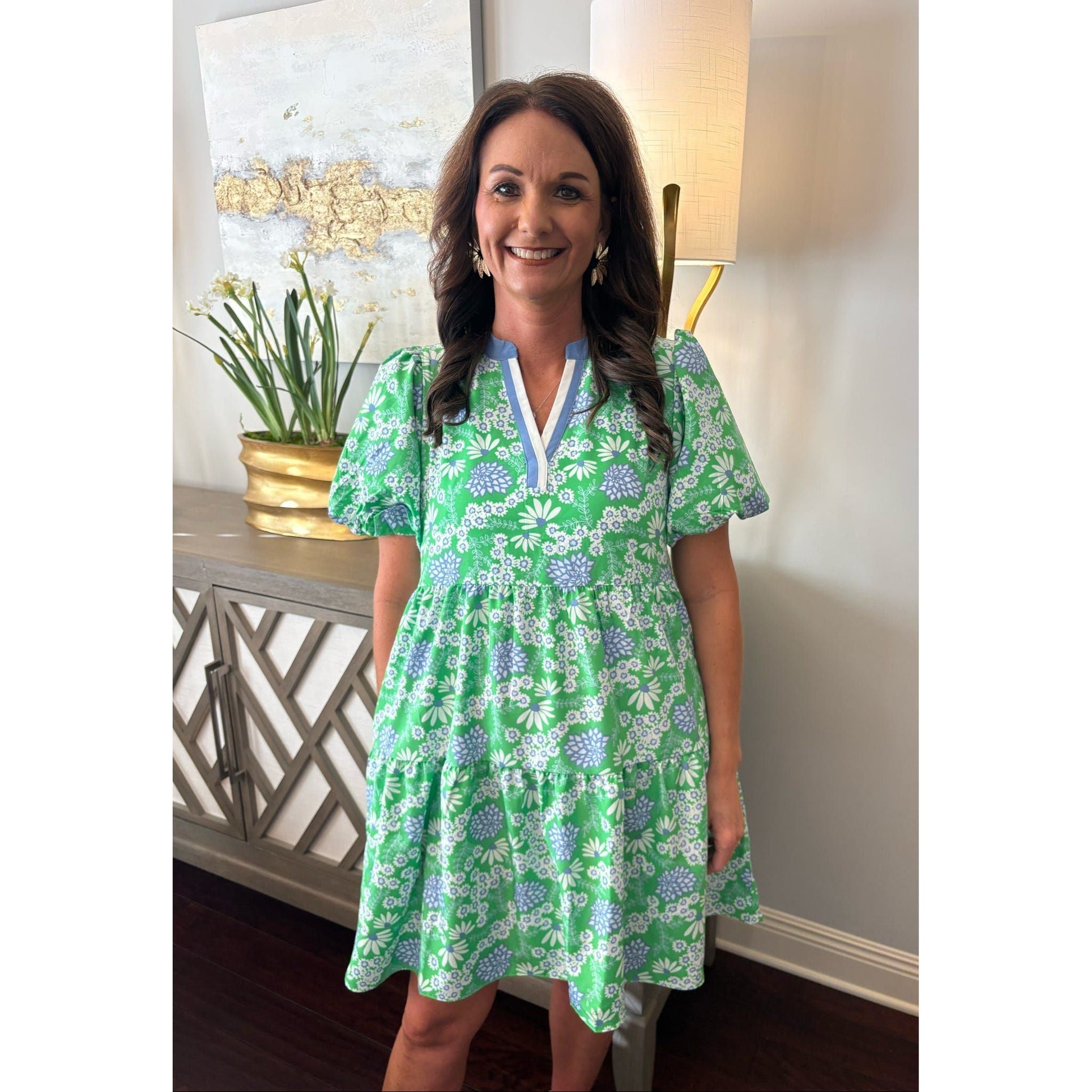 Woman wearing a green floral dress standing indoors.