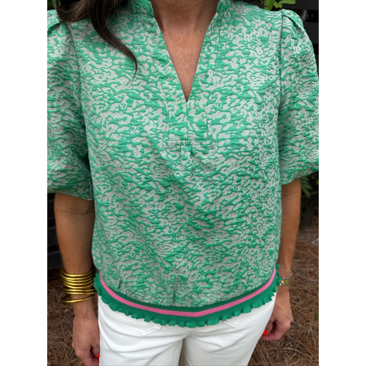 Person wearing a green patterned garment with a pink border.
