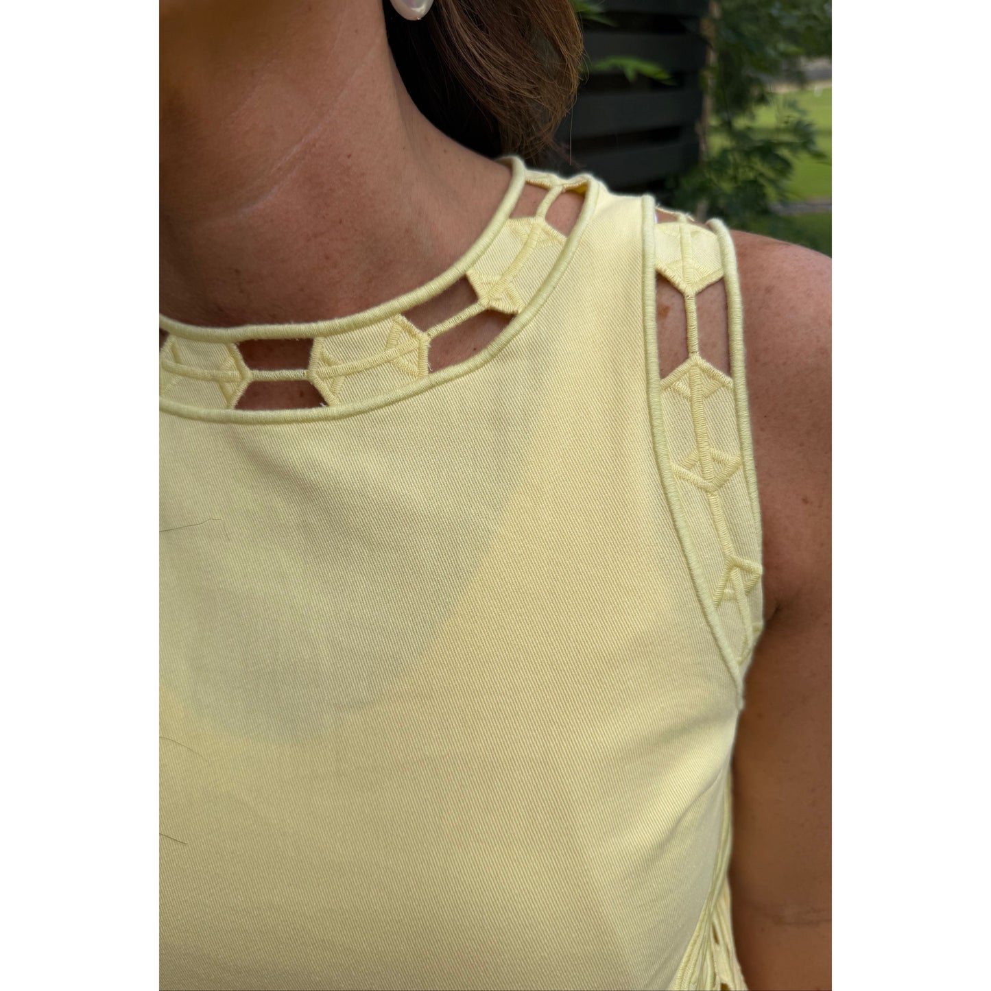 Light yellow top with geometric cut-out details on a person.
