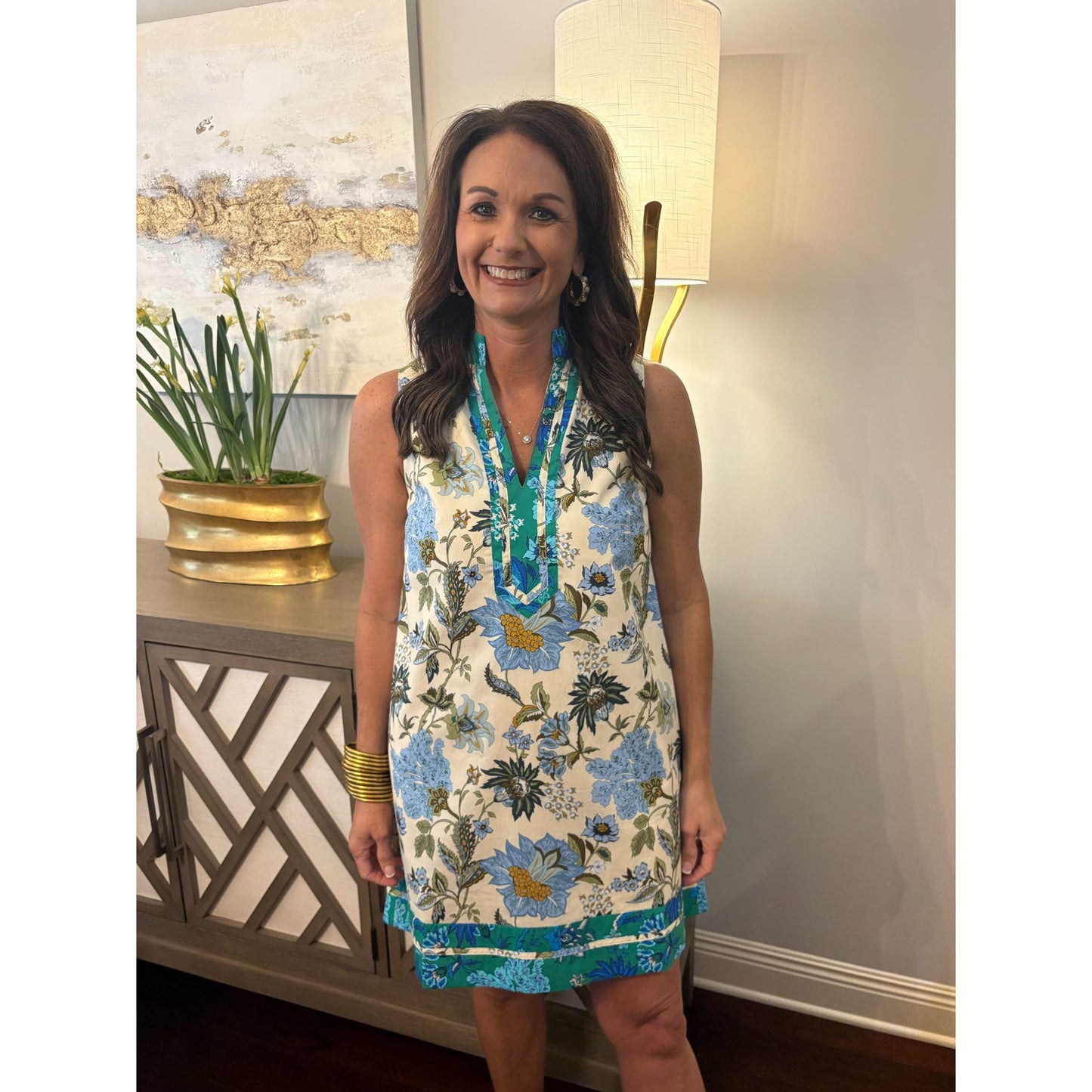 Woman wearing a floral dress standing indoors with decorative elements in the background