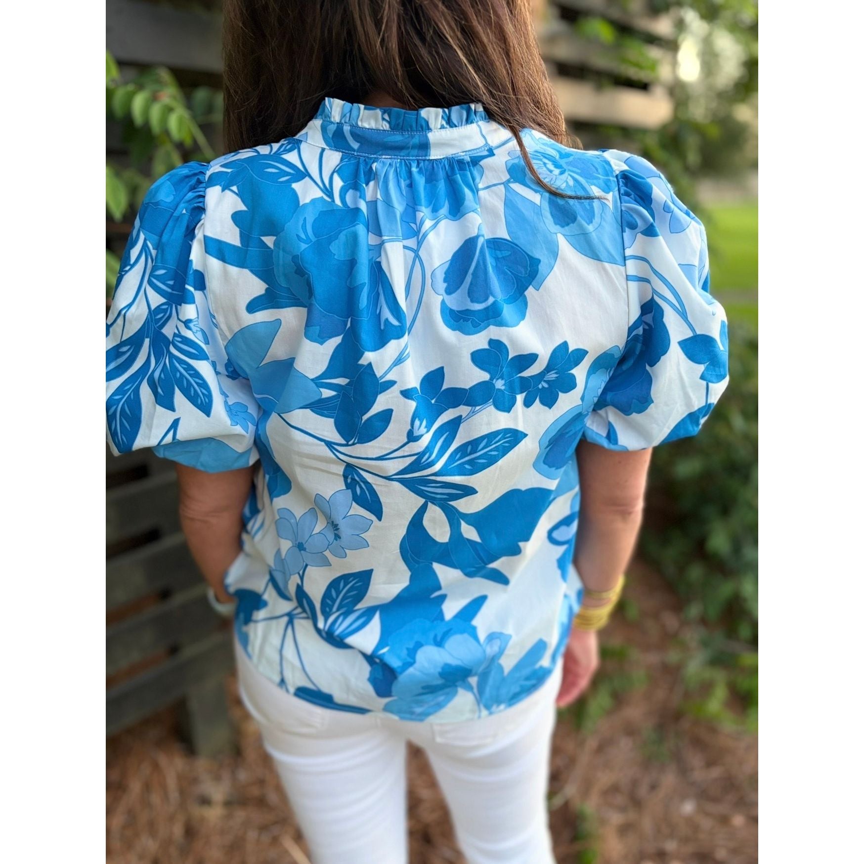 Person wearing a blue floral blouse with white background outdoors