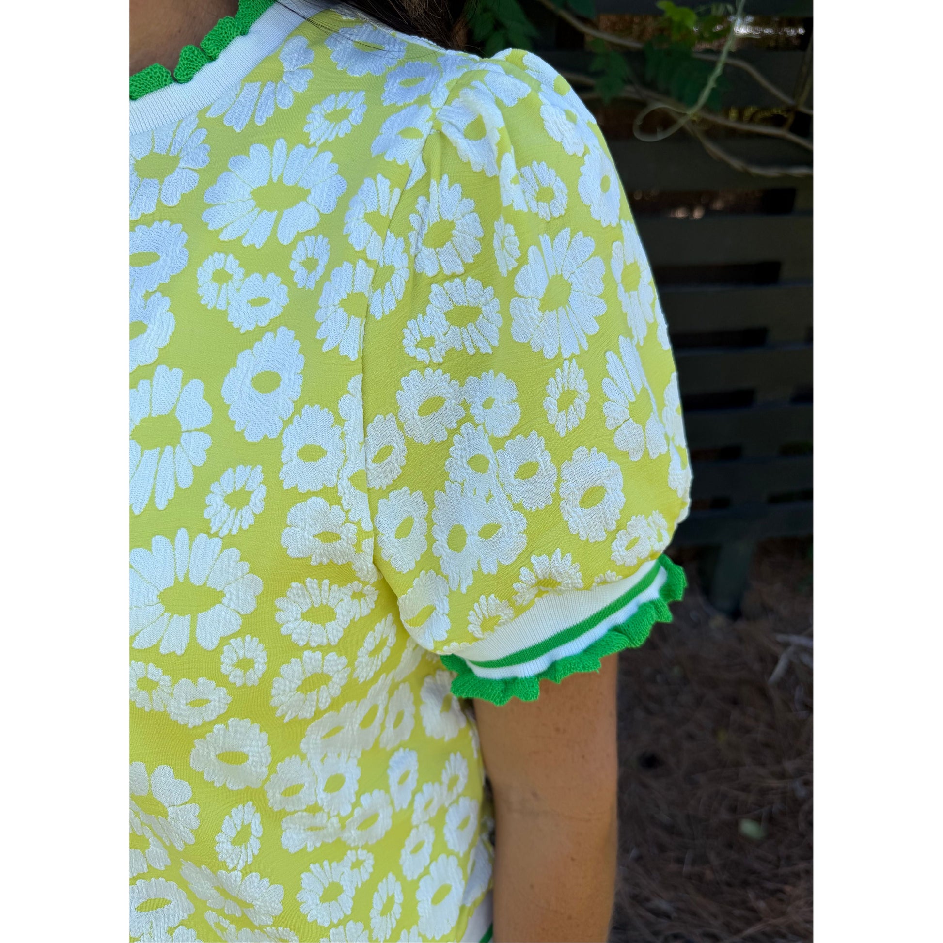 Yellow dress with white floral pattern and green trim on a blurred background