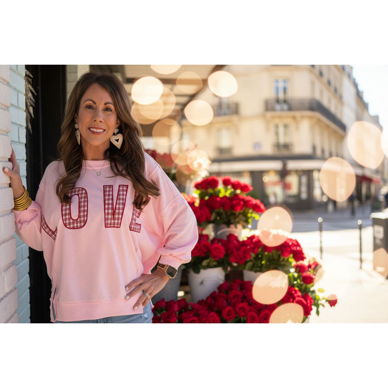 Woman wearing a pink sweatshirt with 'LOVE' printed on it, standing outdoors.