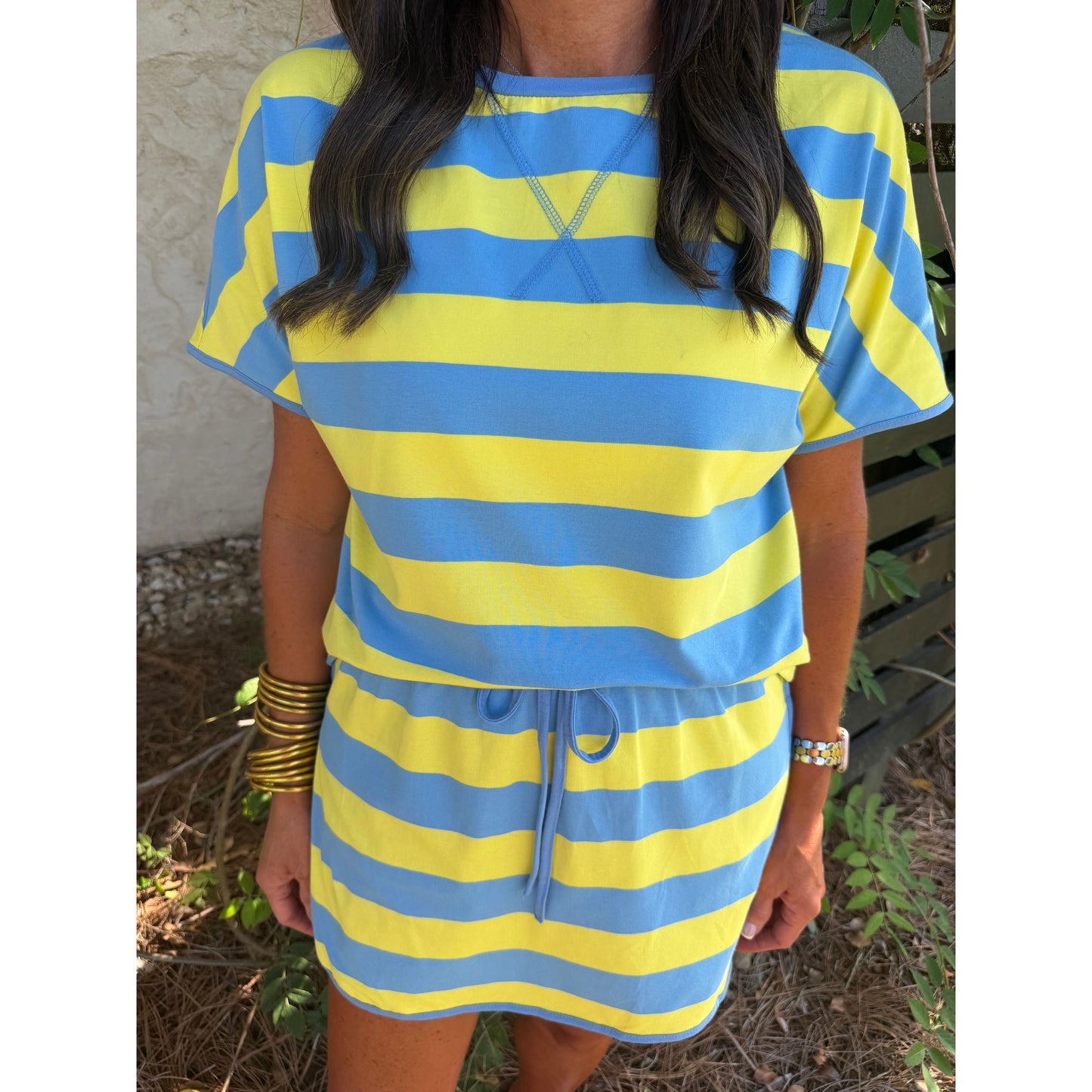 Person wearing a blue and yellow striped dress with a neutral background
