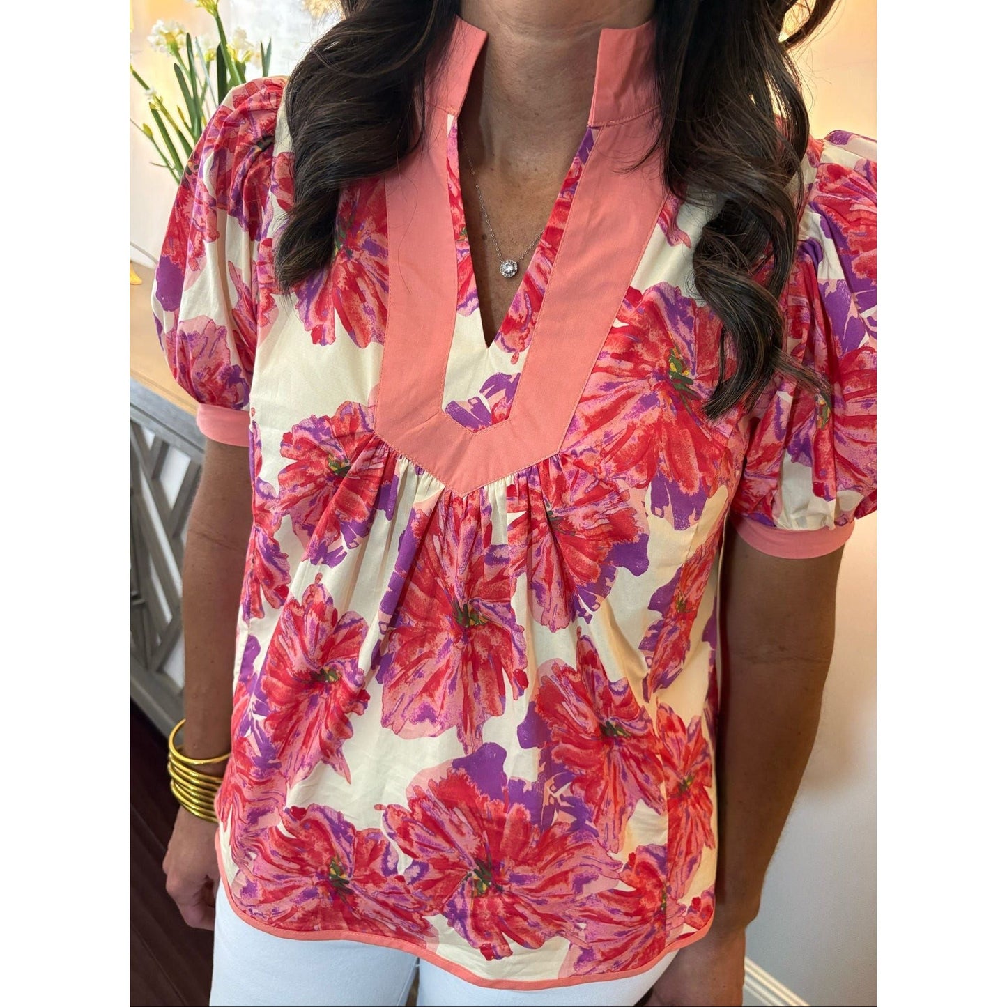 Woman wearing a colorful floral blouse with a neutral background