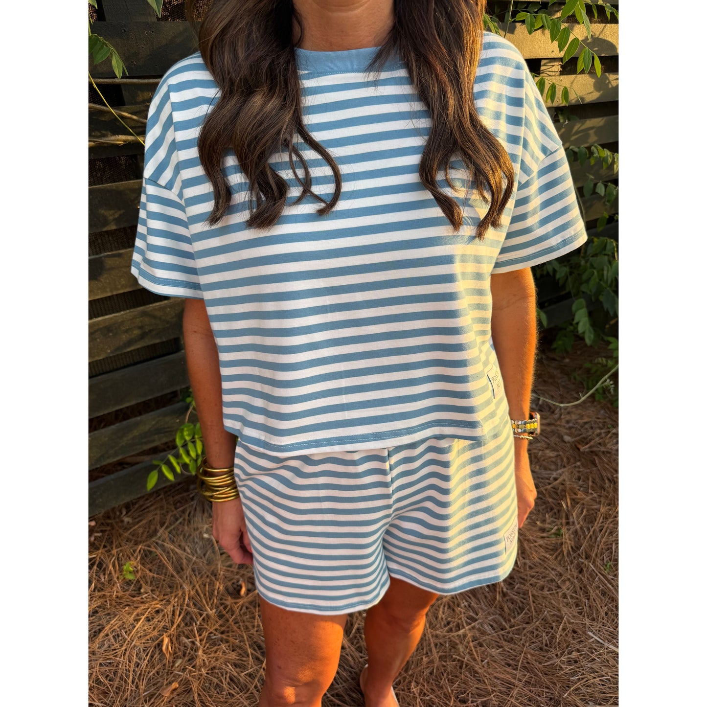 Person wearing a blue and white striped dress sitting outdoors.