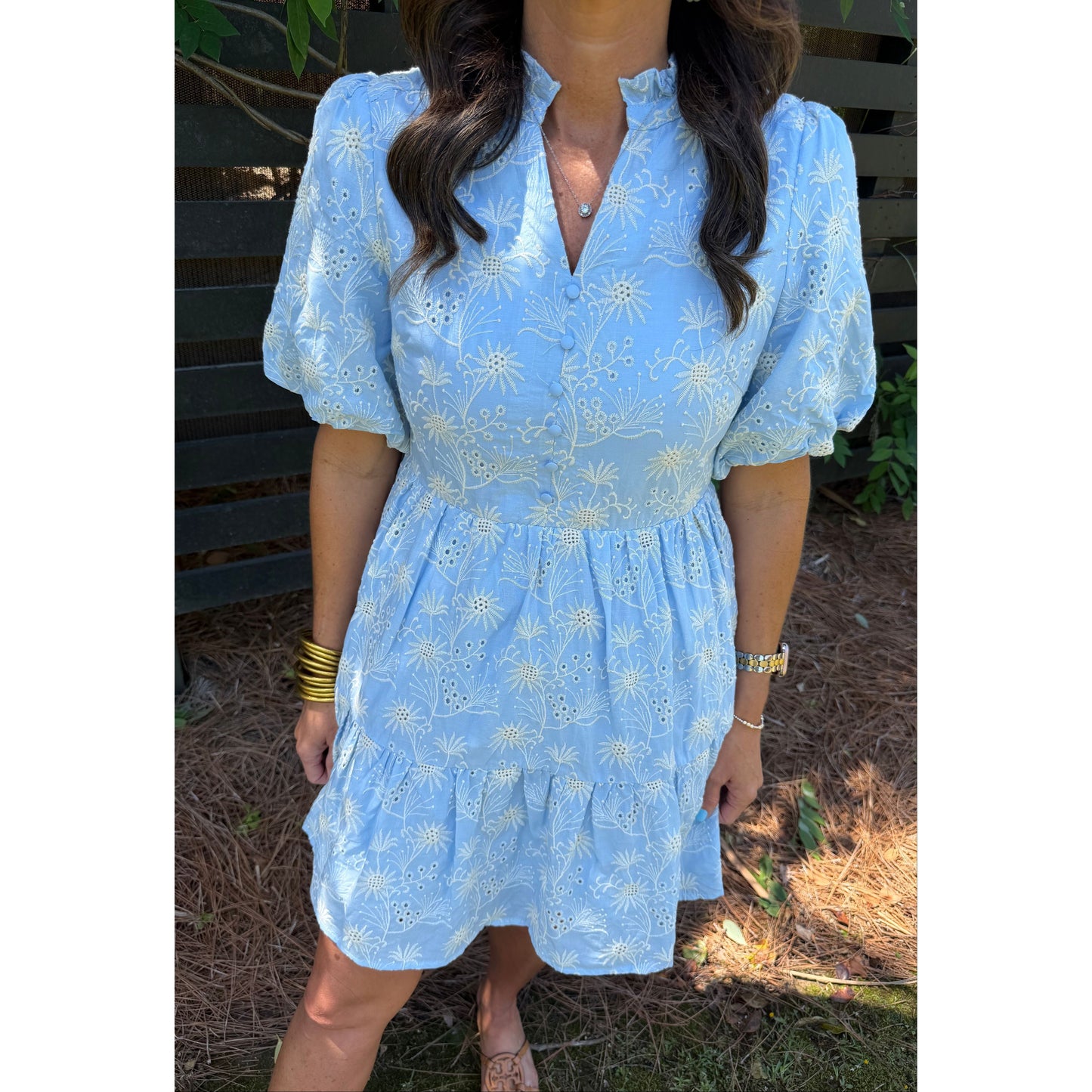 Person wearing a light blue dress with floral patterns outdoors.