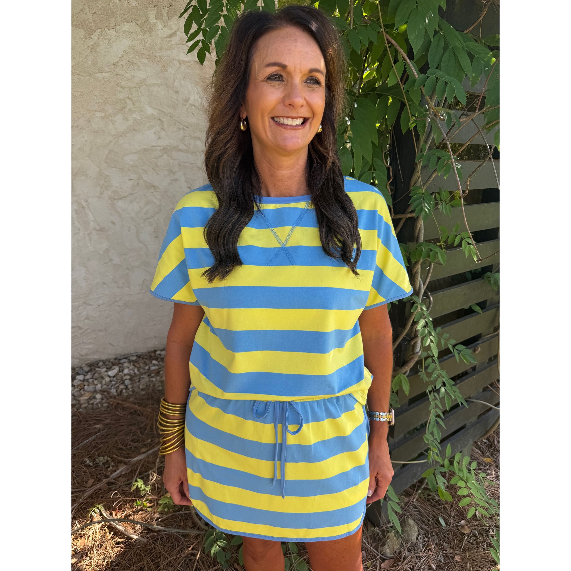 Woman wearing a blue and yellow striped dress standing outdoors.