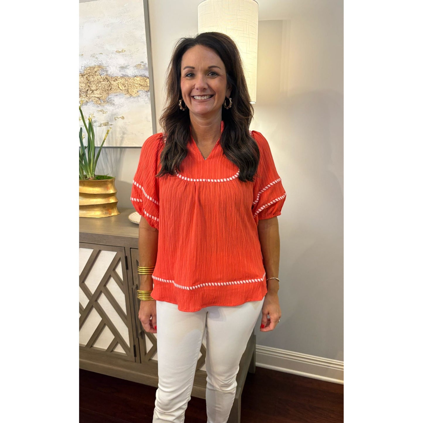 Woman wearing a red blouse with white trim indoors
