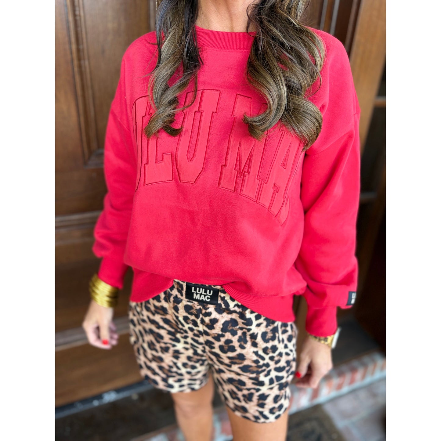 Person wearing a red sweatshirt with 'Lululemon' branding and leopard print shorts.