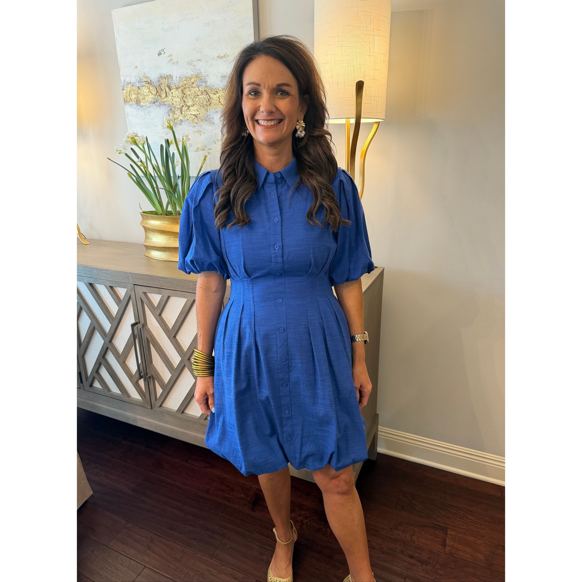 Woman in a blue dress standing in a room with decorative elements.