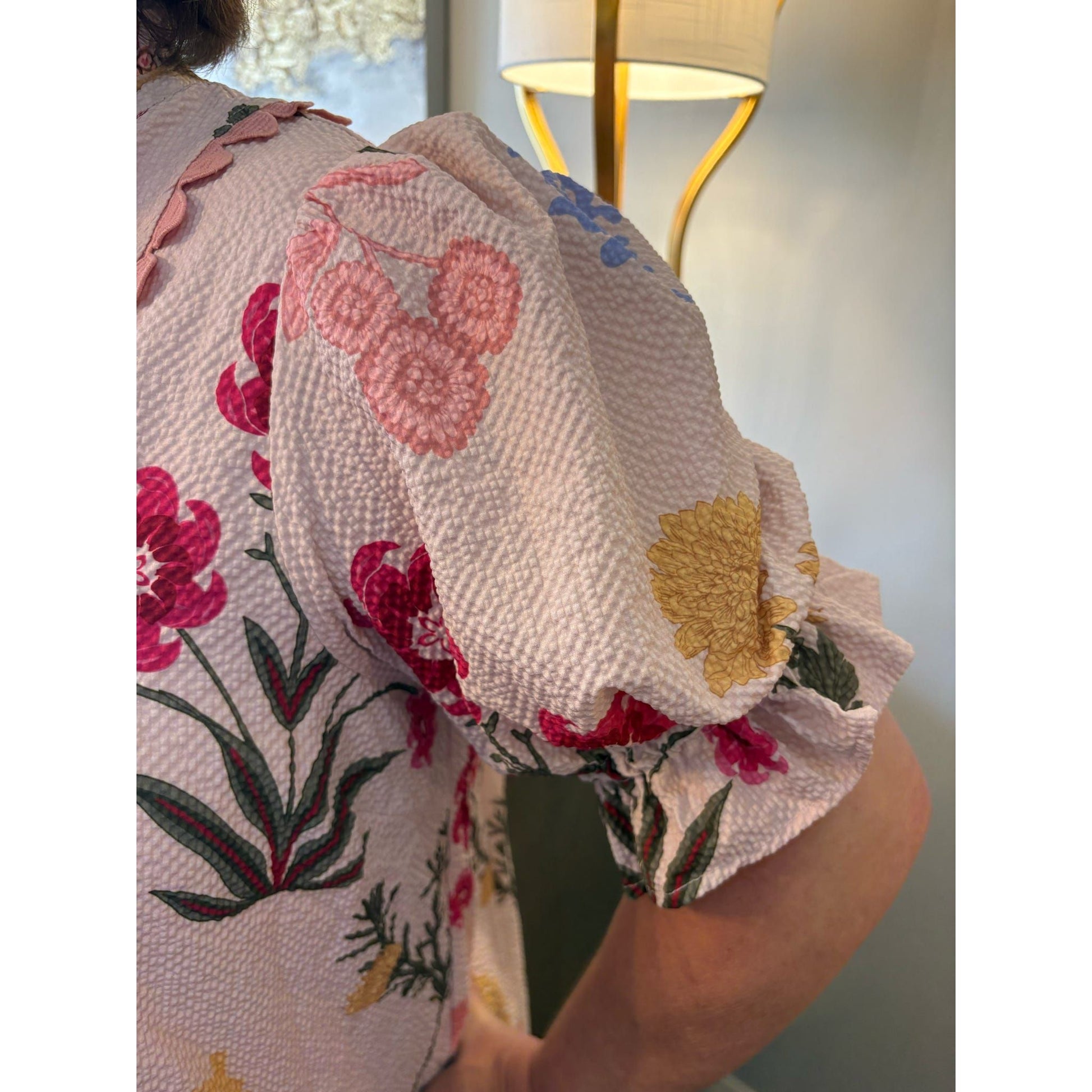 Person wearing a floral-patterned garment with a blurred background