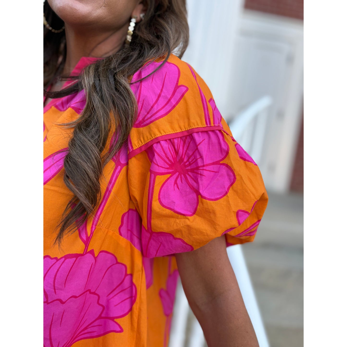 Person wearing an orange and pink floral dress with blurred background