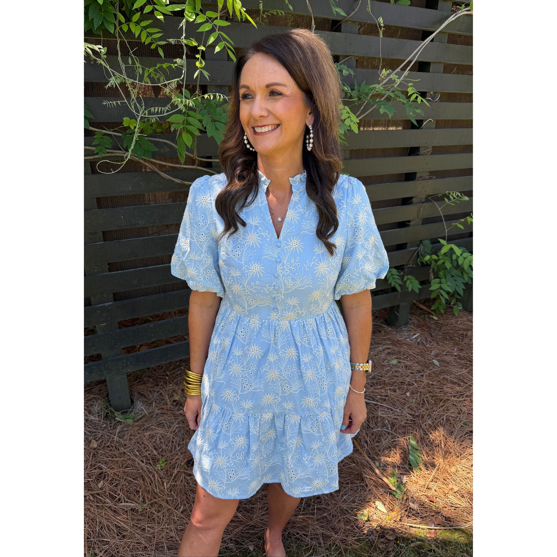 Woman in a blue dress standing outdoors with plants around