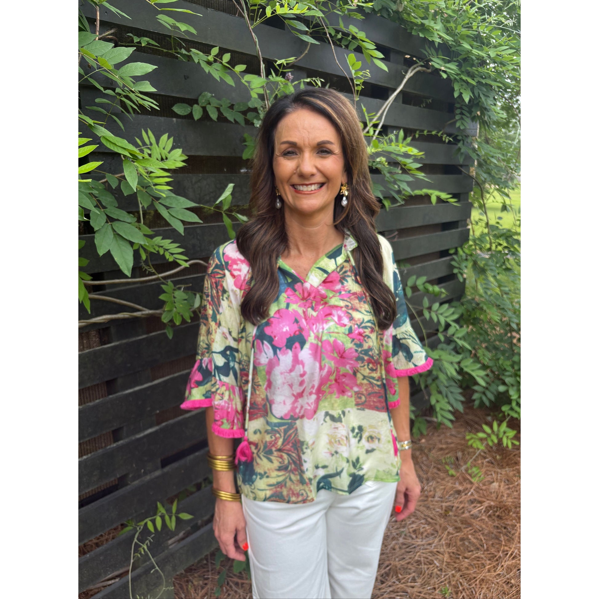 Woman wearing a floral jacket standing outdoors with greenery around
