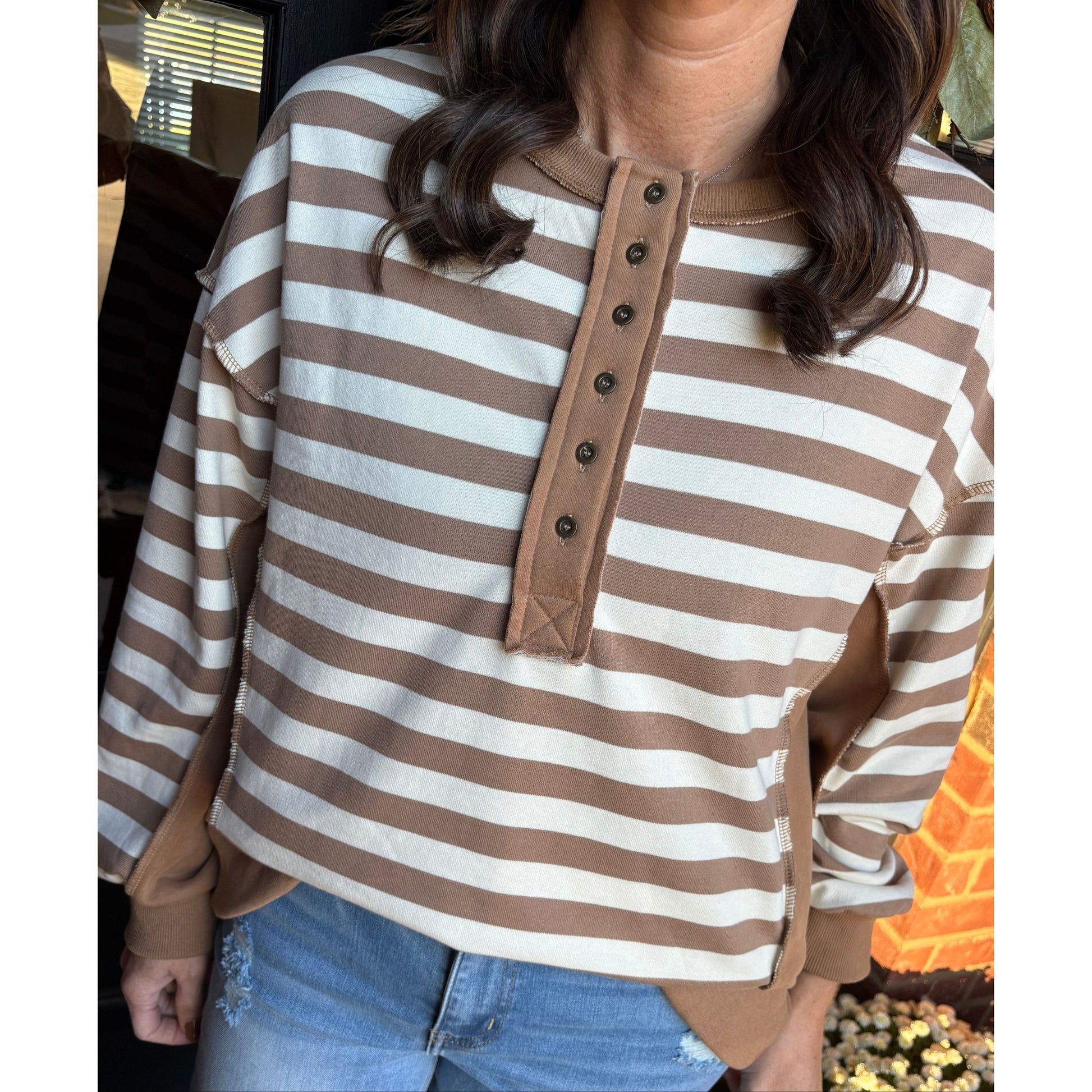 Person holding a brown and white striped bag with a blurred background