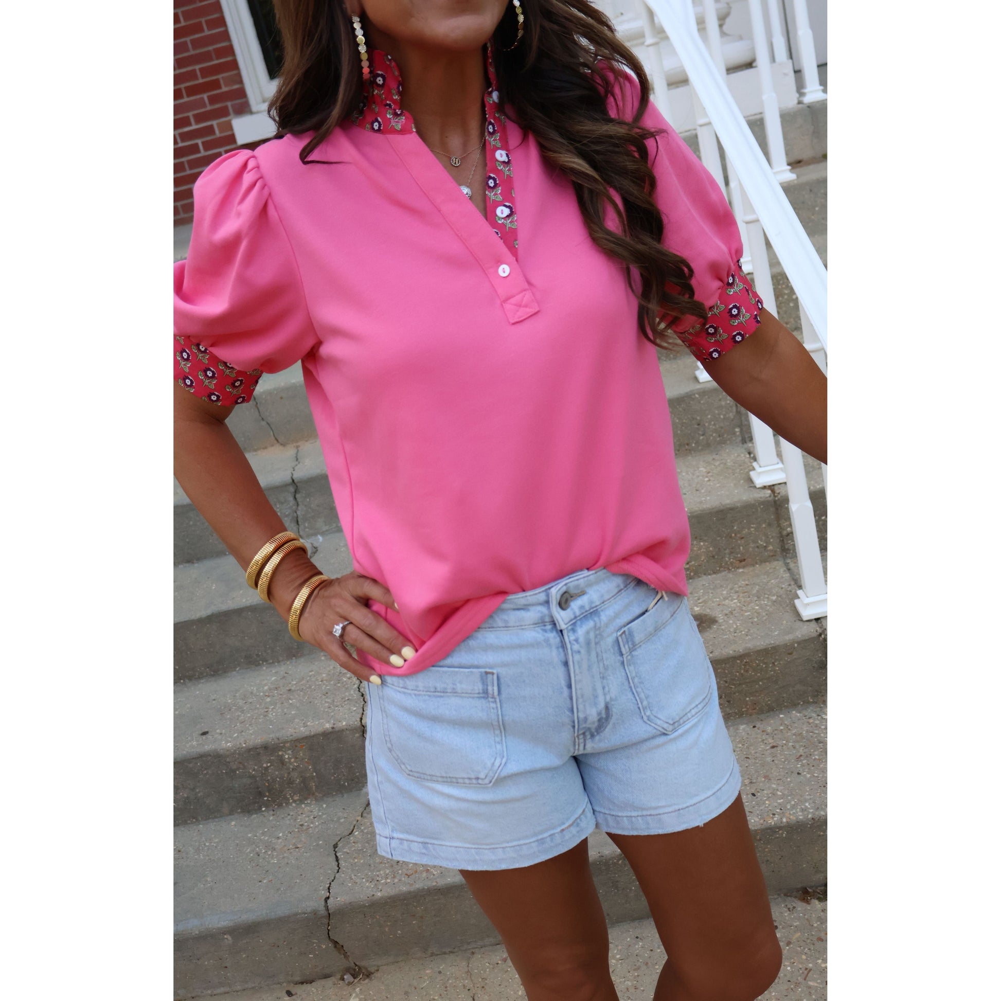 Person wearing a pink top and denim shorts on a staircase.