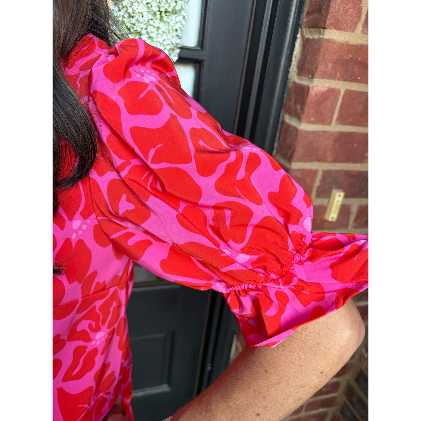 Person wearing a bright pink and red patterned garment with a blurred background