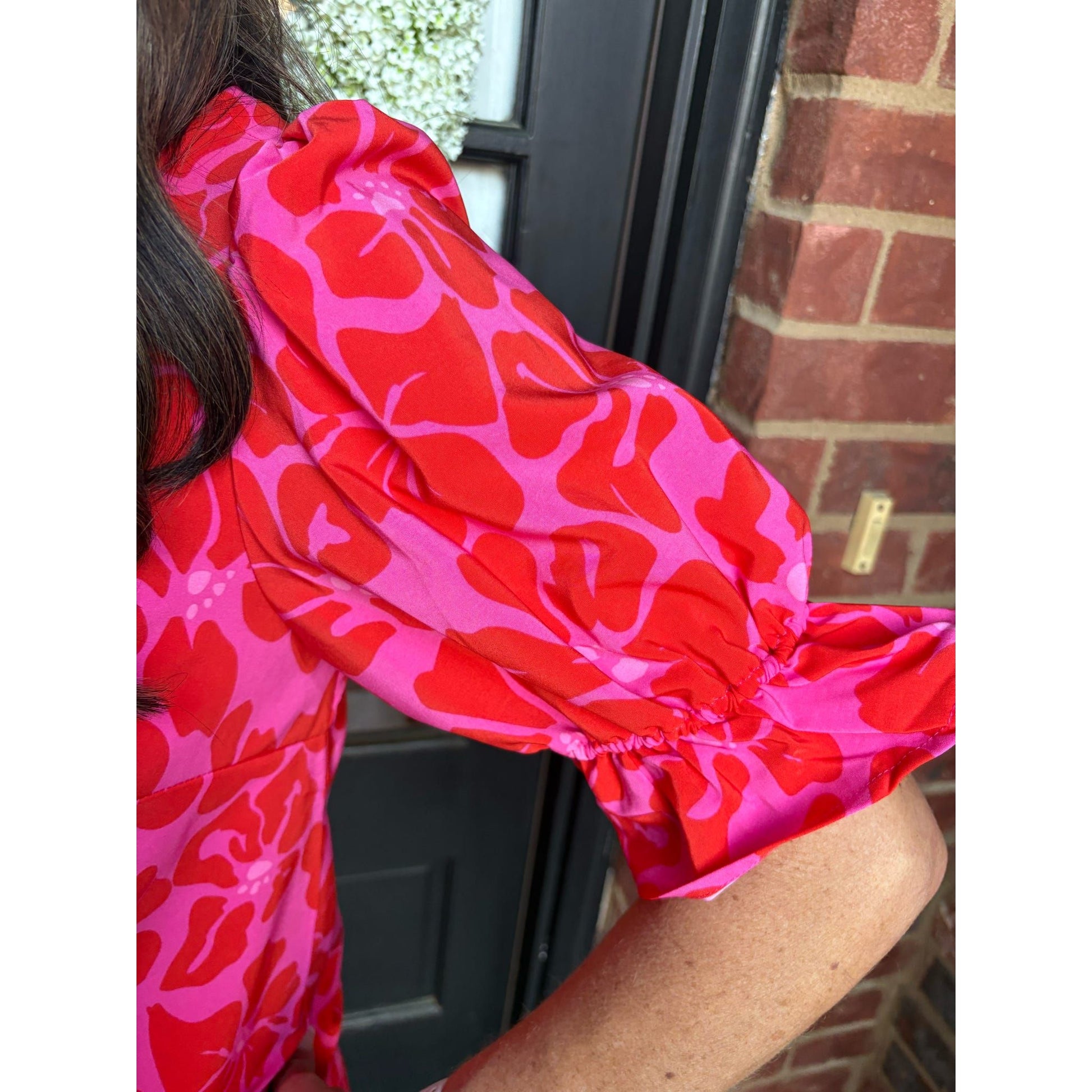 Person wearing a bright pink and red patterned garment with a blurred background