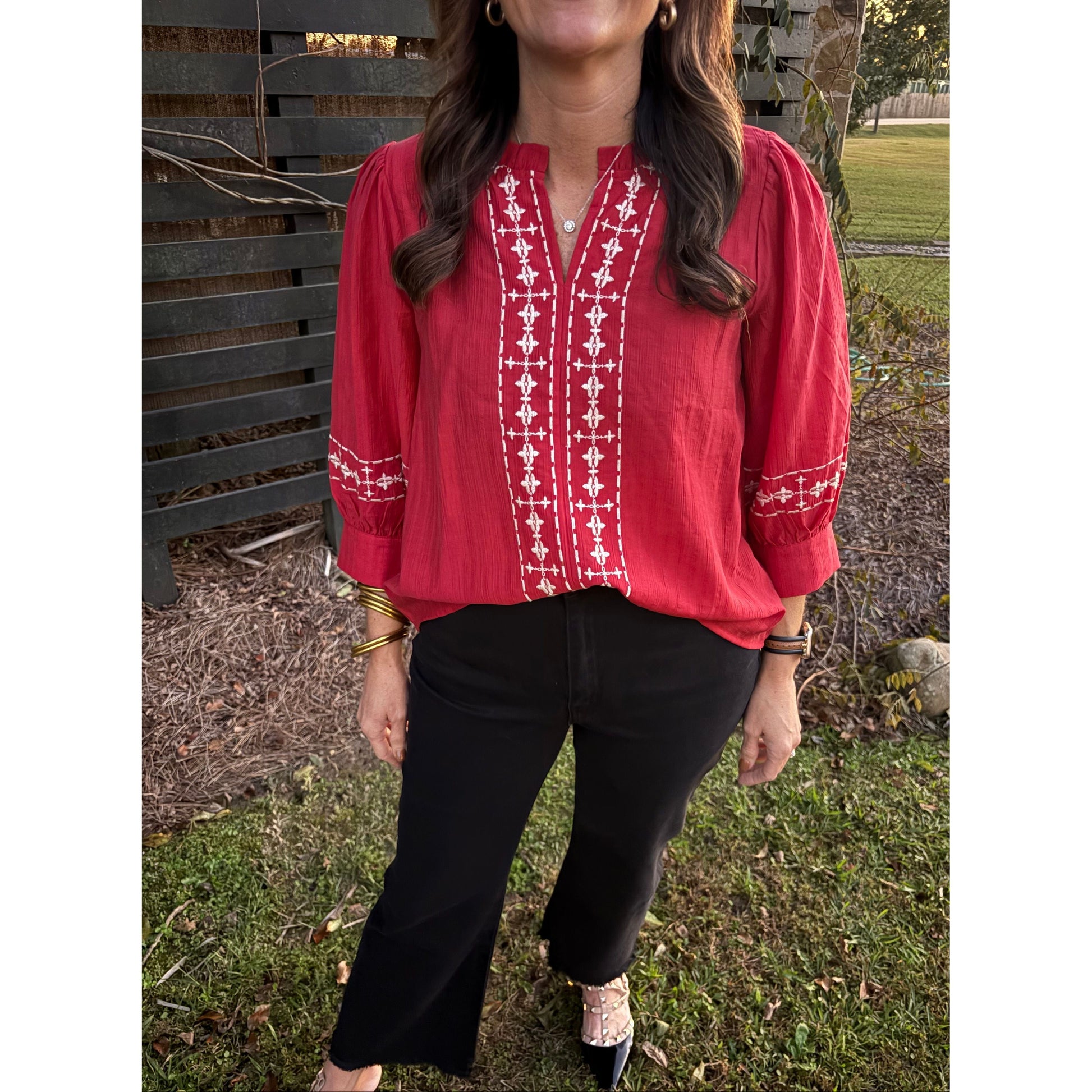 Person wearing a red patterned shirt outdoors on a grassy area