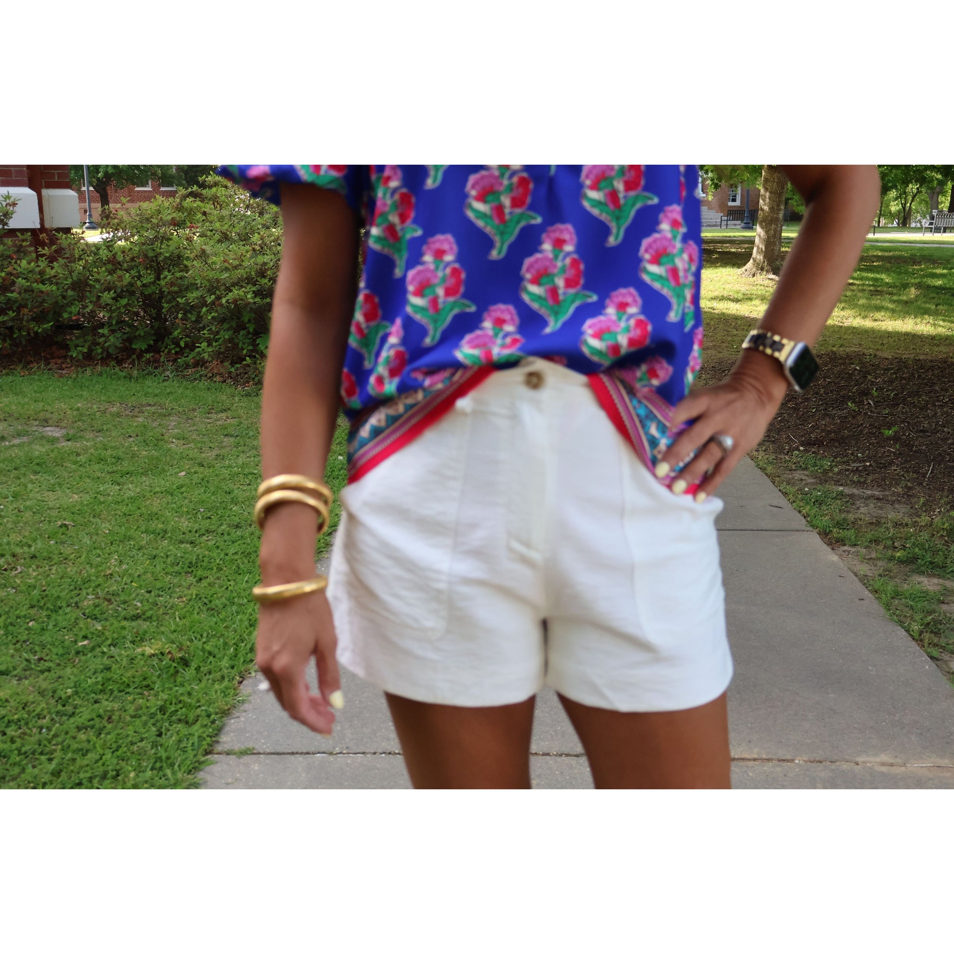 Person wearing a colorful floral shirt and white shorts outdoors.