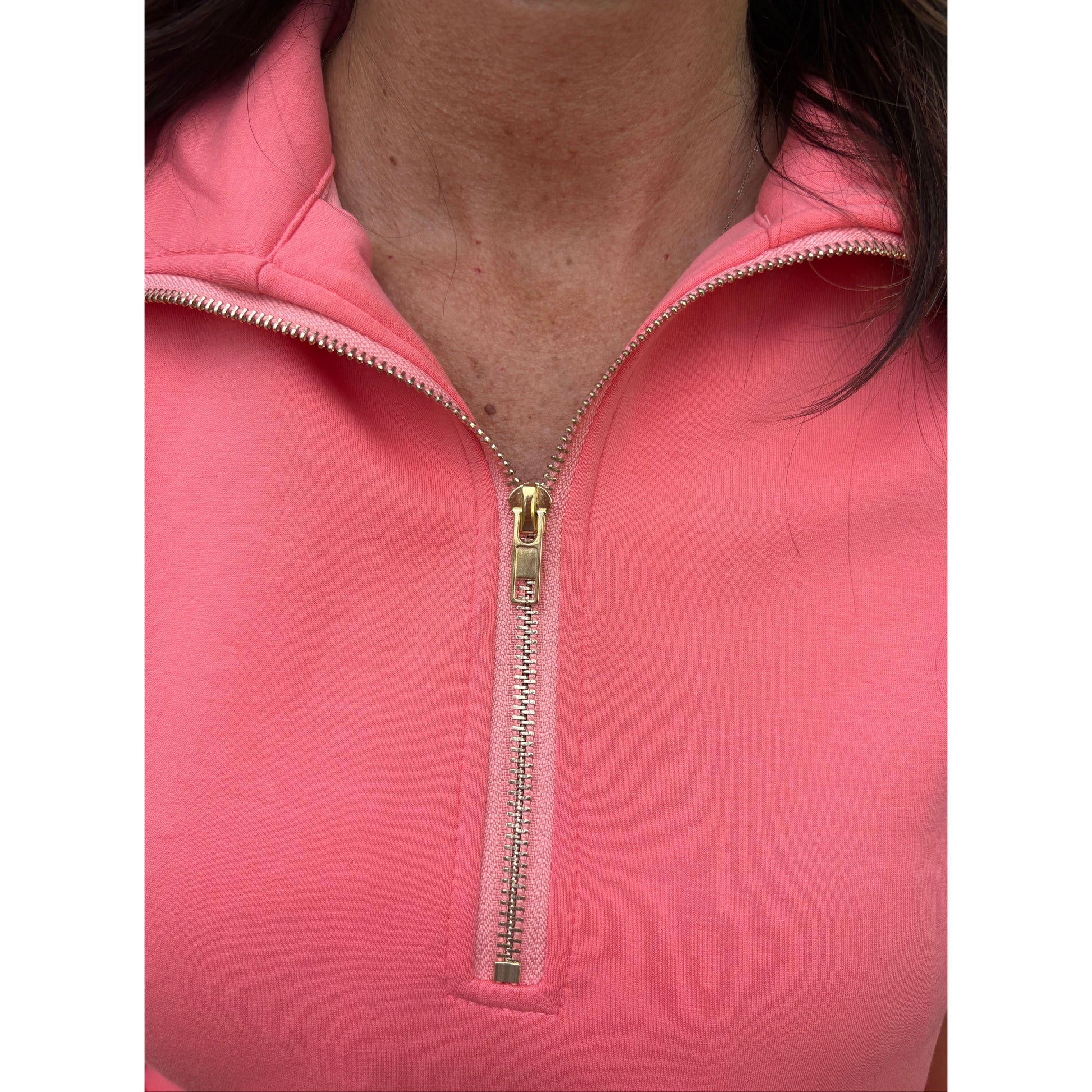 Close-up of a pink zip-up garment with a gold zipper.