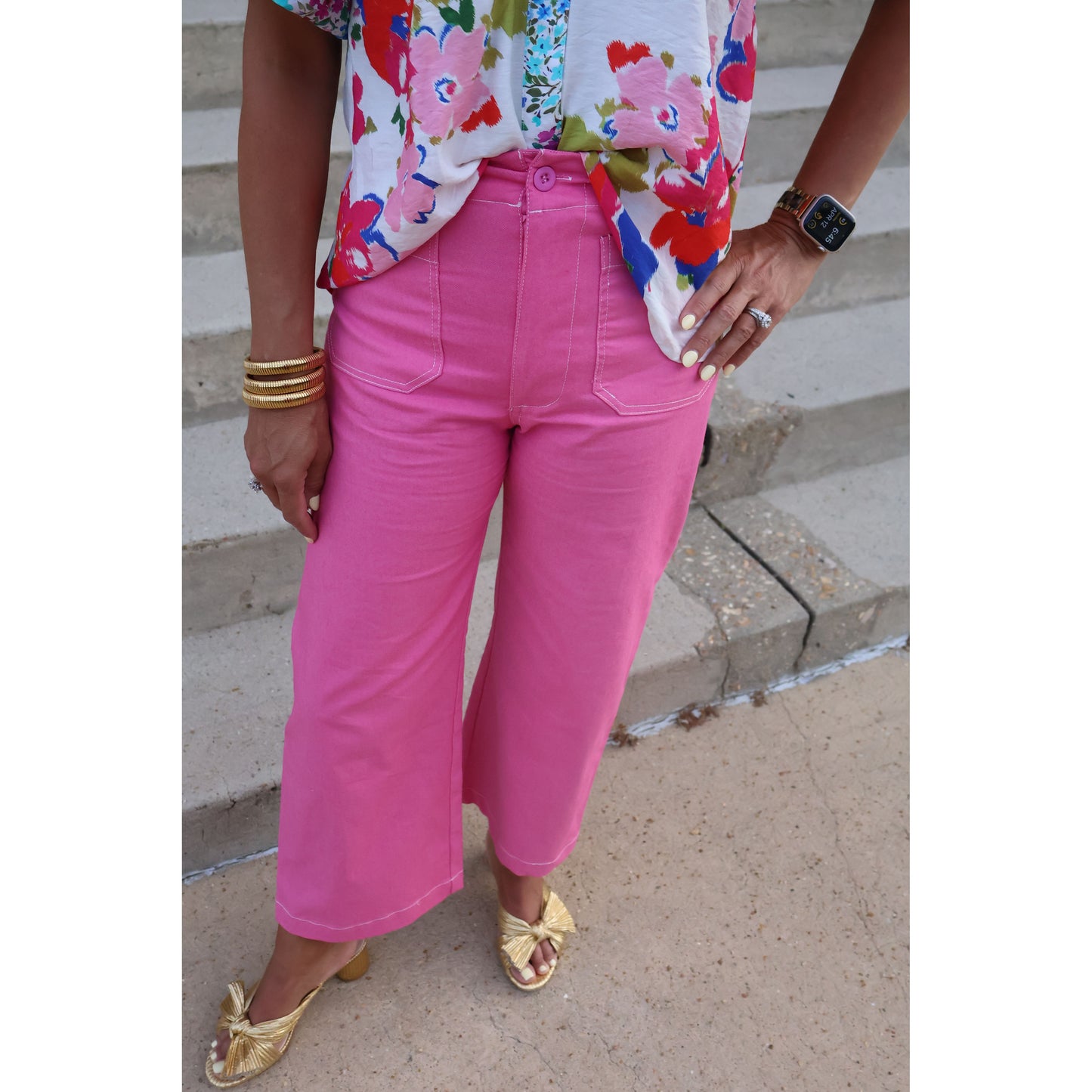 Person wearing bright pink pants and a colorful top, standing on a concrete surface.